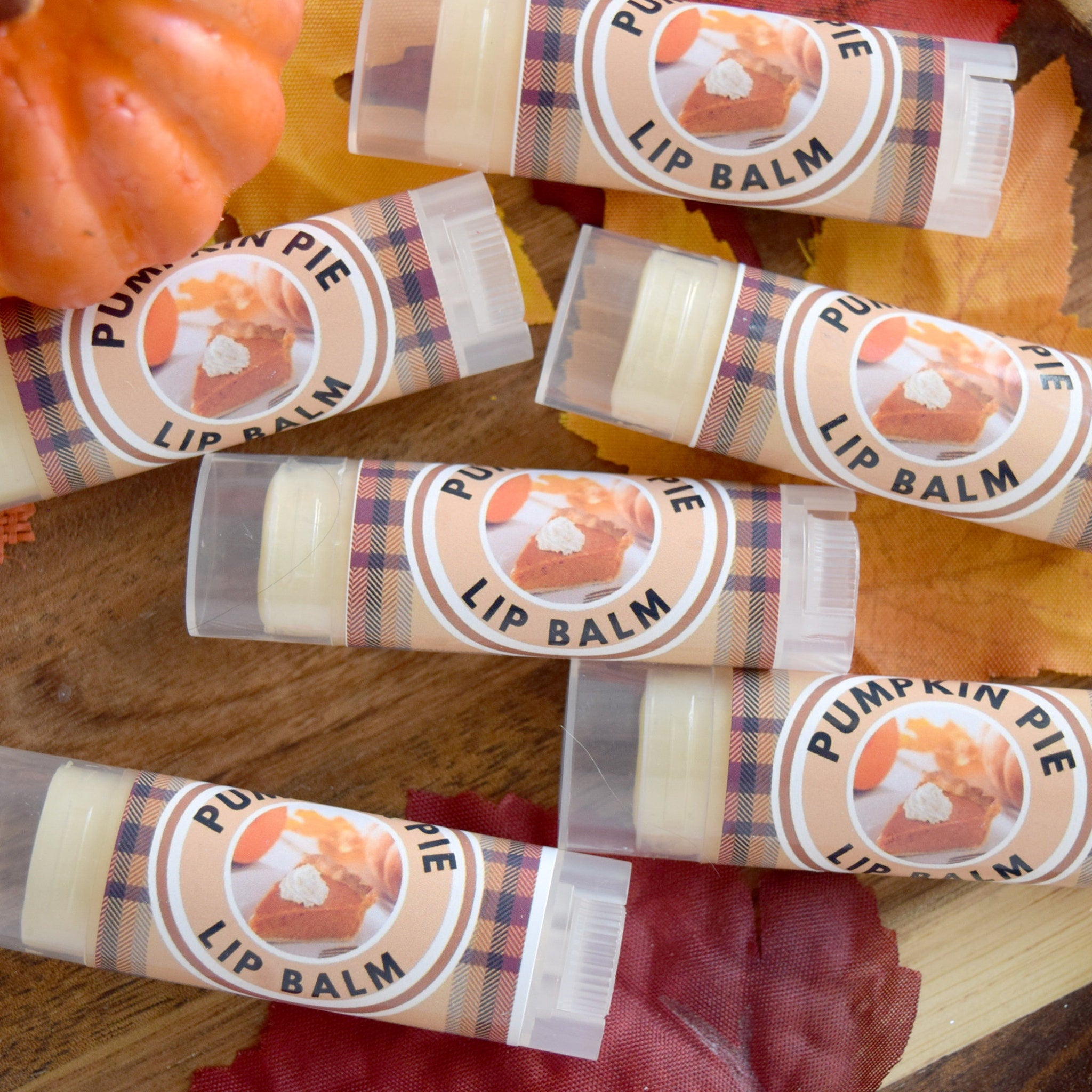Lip balm tubes with pumpkin pie label, plaid pattern, clear plastic casing, and visible text
