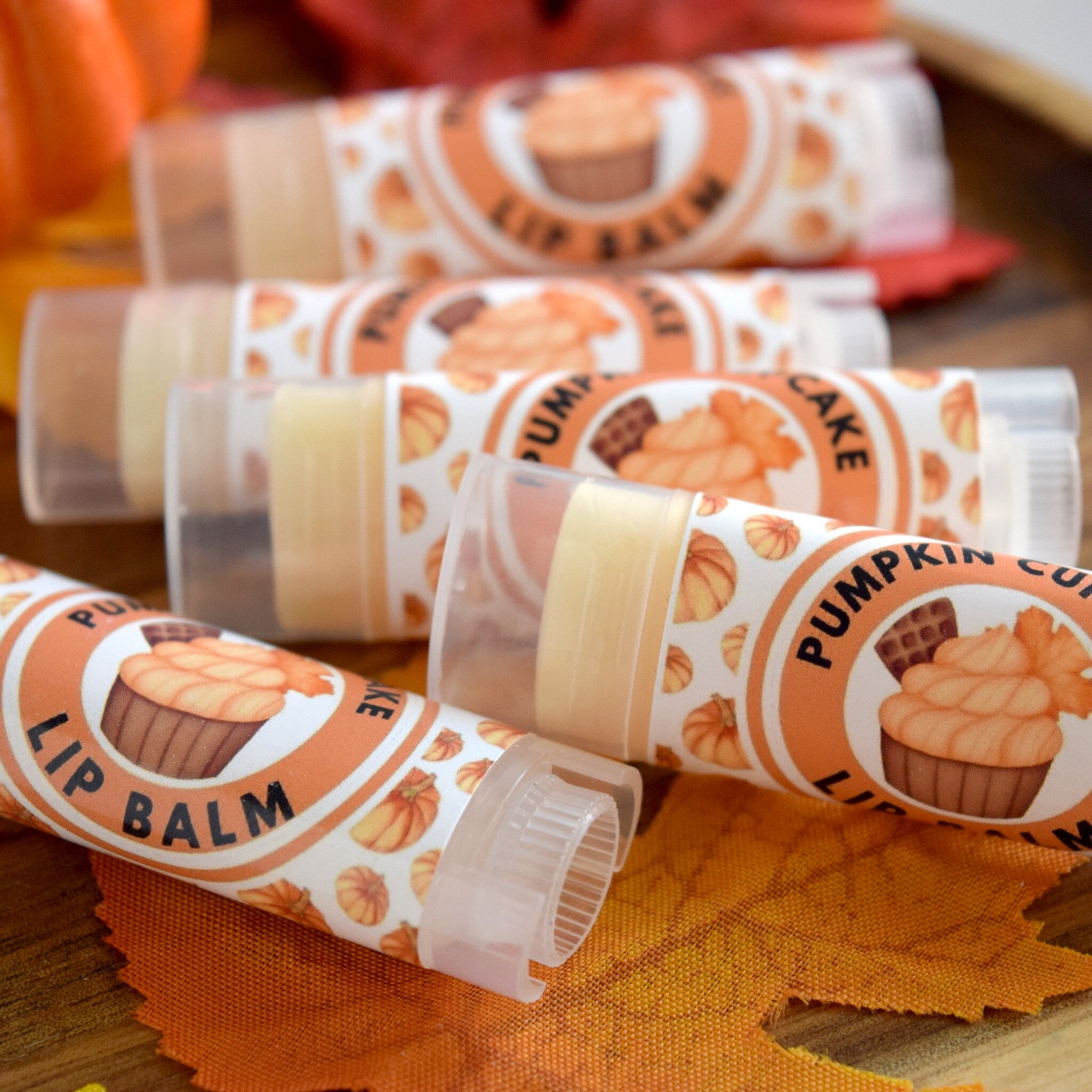 Pumpkin lip balm tubes with orange and white labels, clear plastic, and pumpkin illustrations