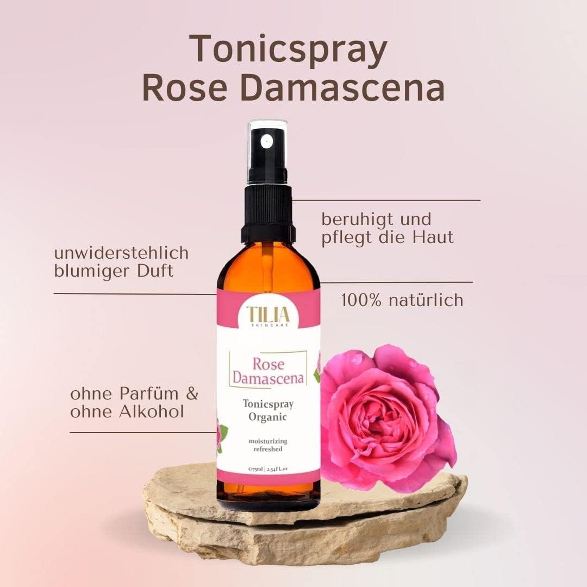 Tonic spray bottle with black spray top, amber liquid, and pink label, next to a pink rose on a rock