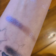 Side view of two purple eye shadow pans showing satin and shimmer finishes in compact palette