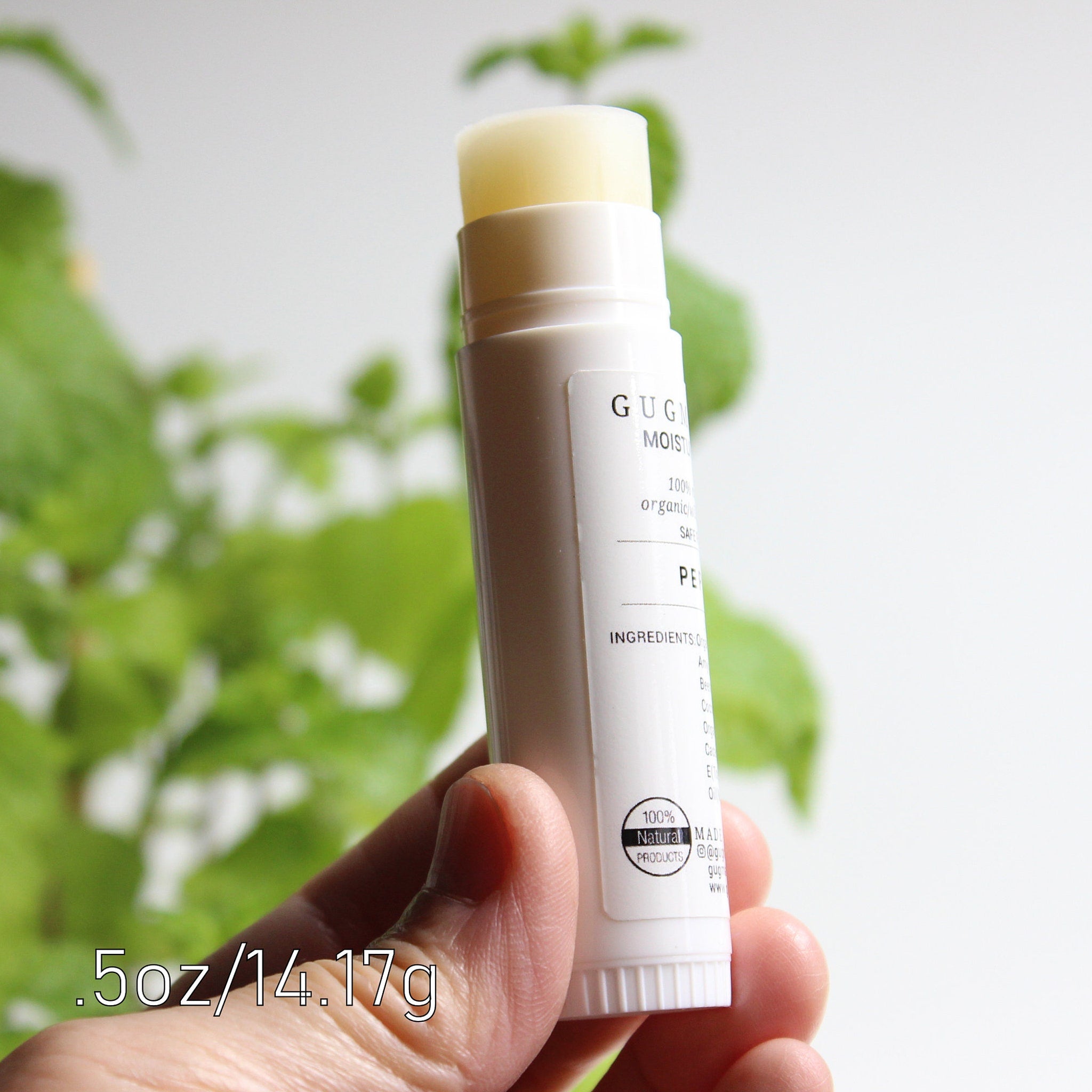 Lip balm stick with white tube, yellow balm, and GUG label held in hand
