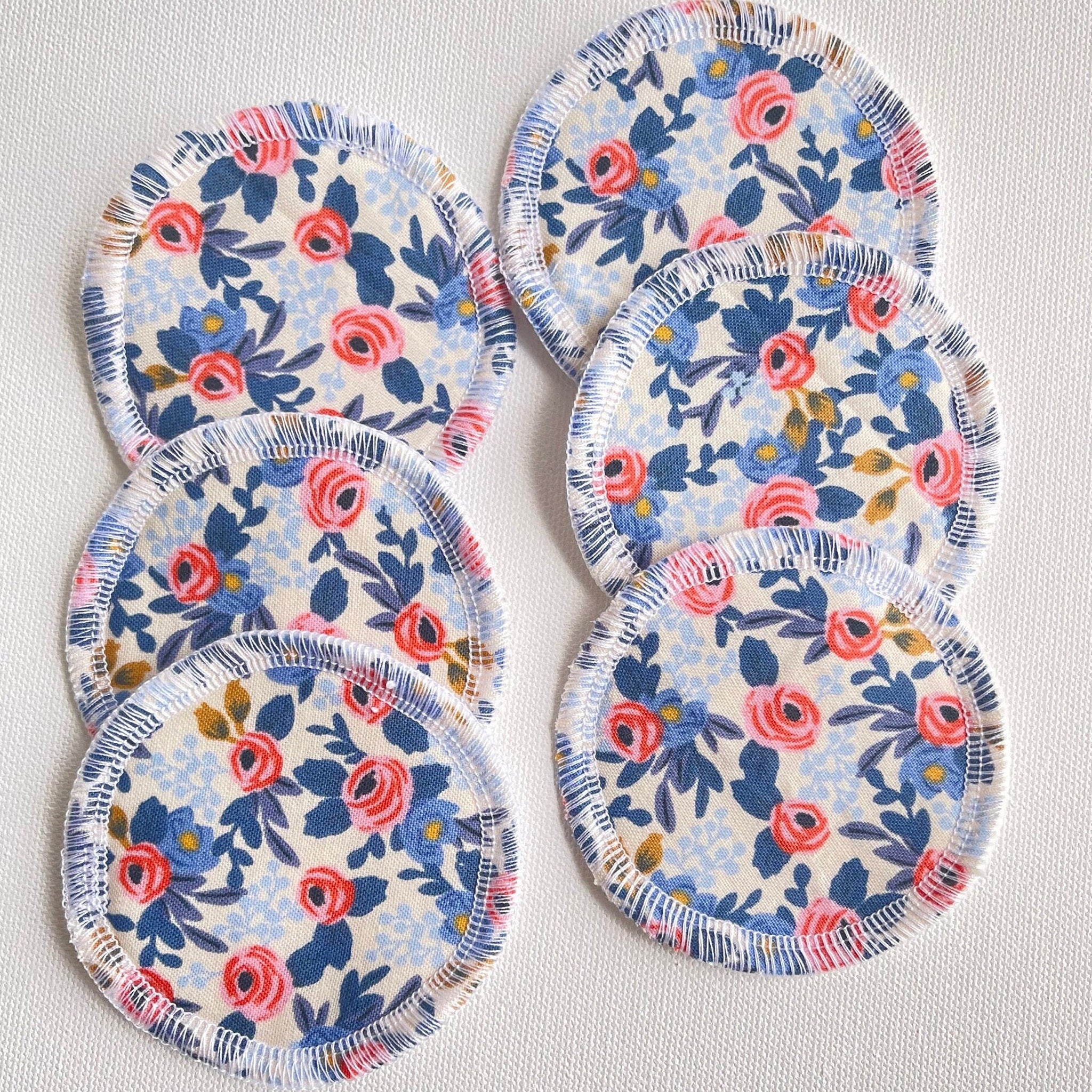 Reusable face pads with floral pattern, white stitching, and blue, pink, and cream colors