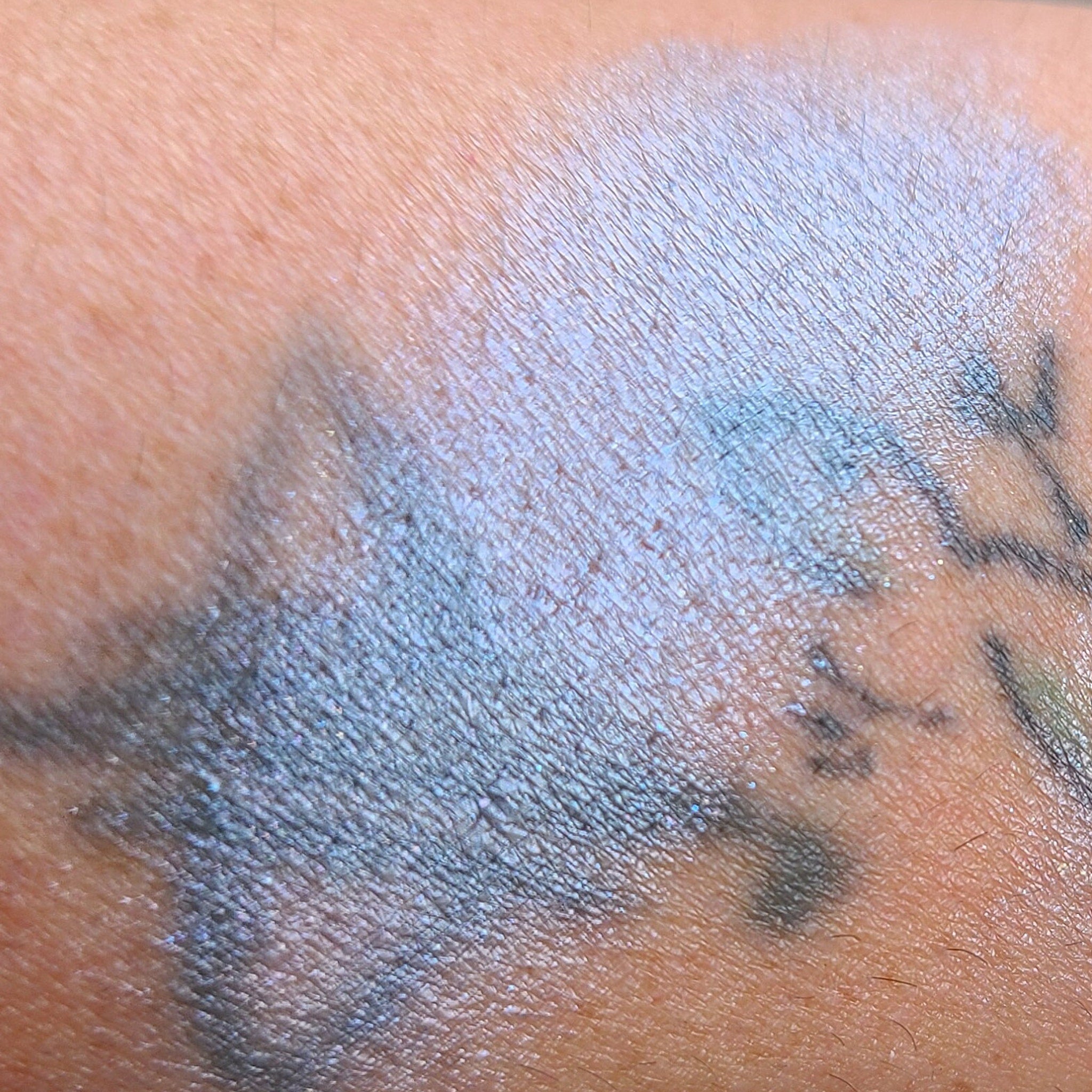 Side view of creamy pastel blue eyeshadow palette with fluffy cloud-shaped embossing on compact