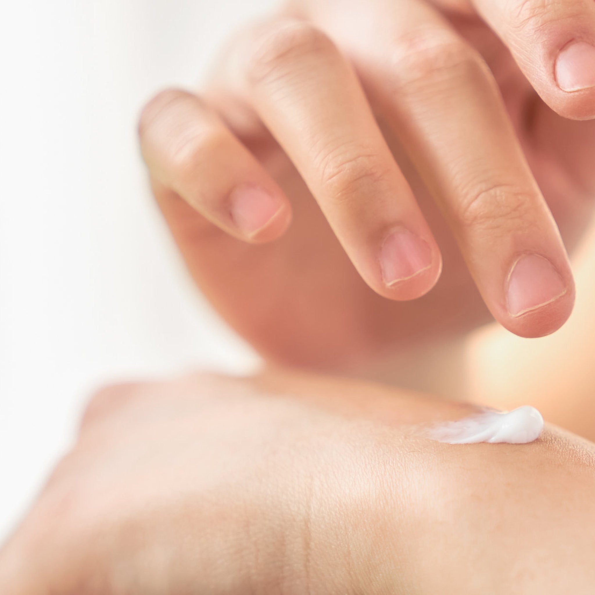 Hand cream application, white cream on skin, close-up of hand and cream use