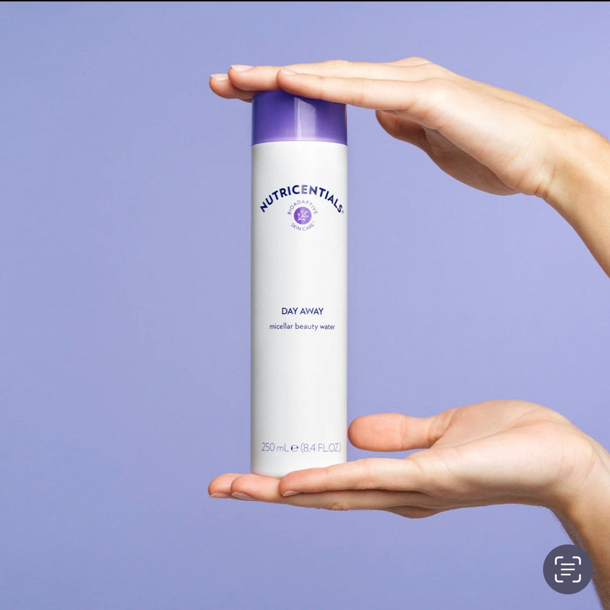 Facial cleanser bottle, white and purple, held by hands, Nutricentials brand visible