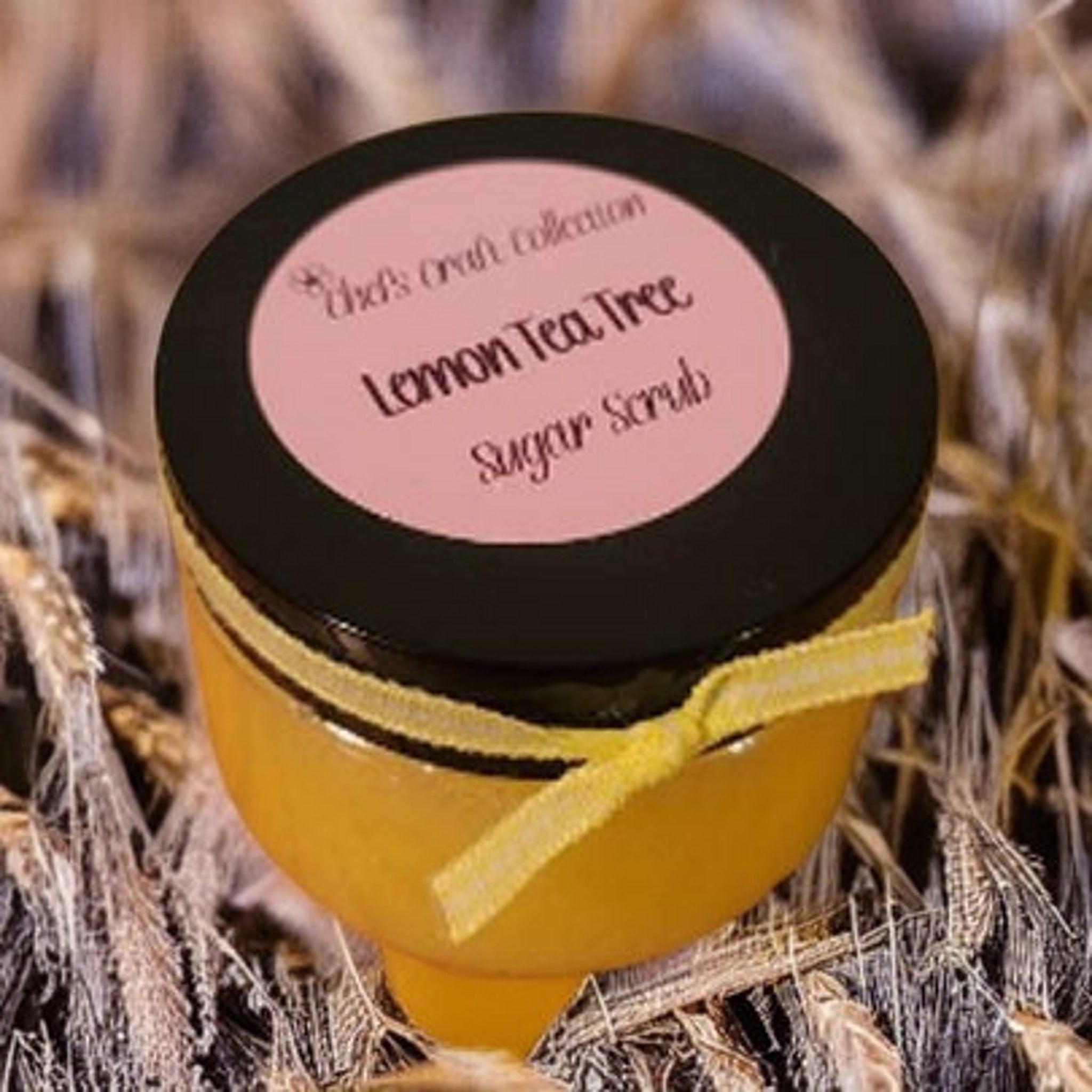 Sugar scrub jar with black lid, yellow ribbon, and "Lemon Tea Tree" label text