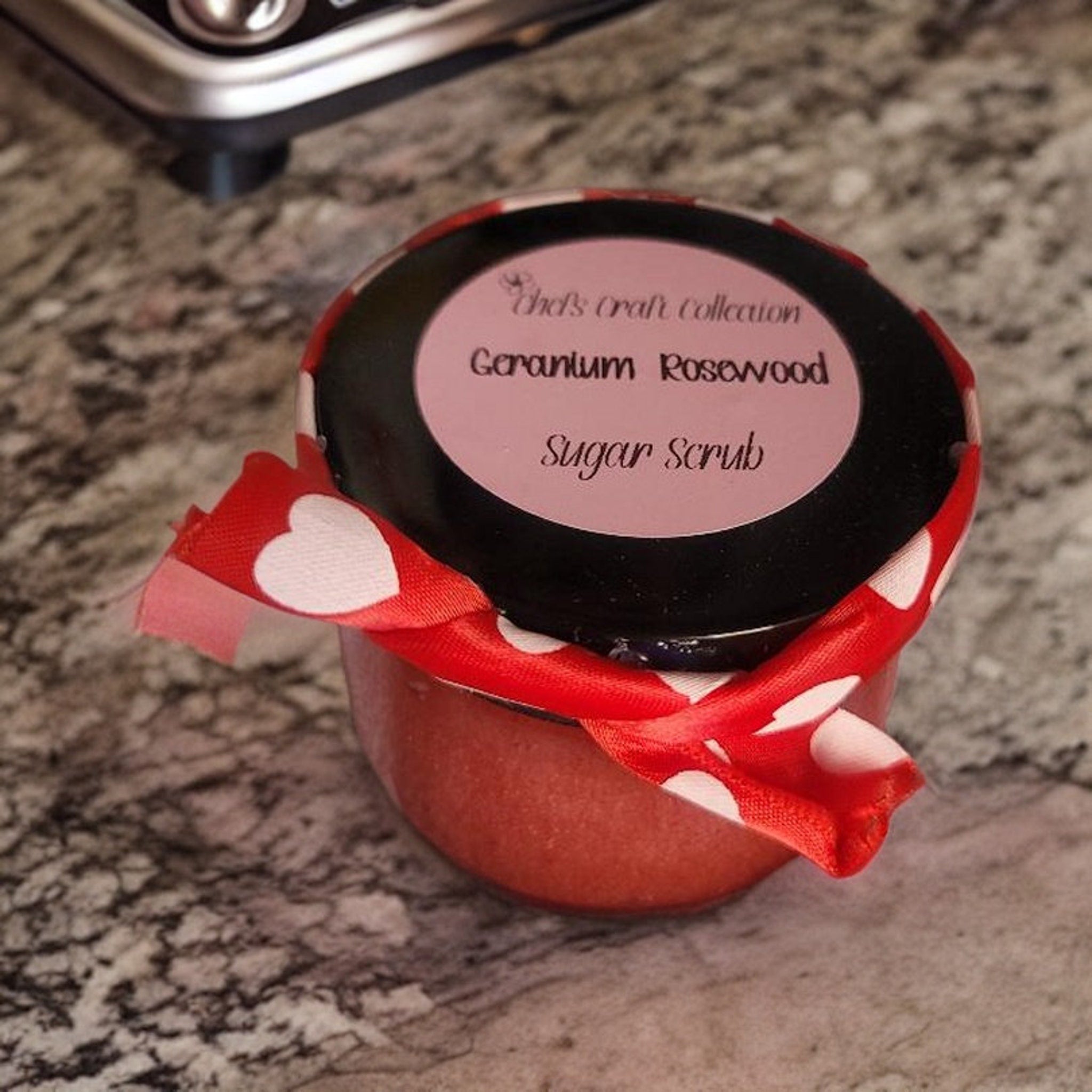 Sugar scrub jar with red ribbon, white heart pattern, and black lid with text label
