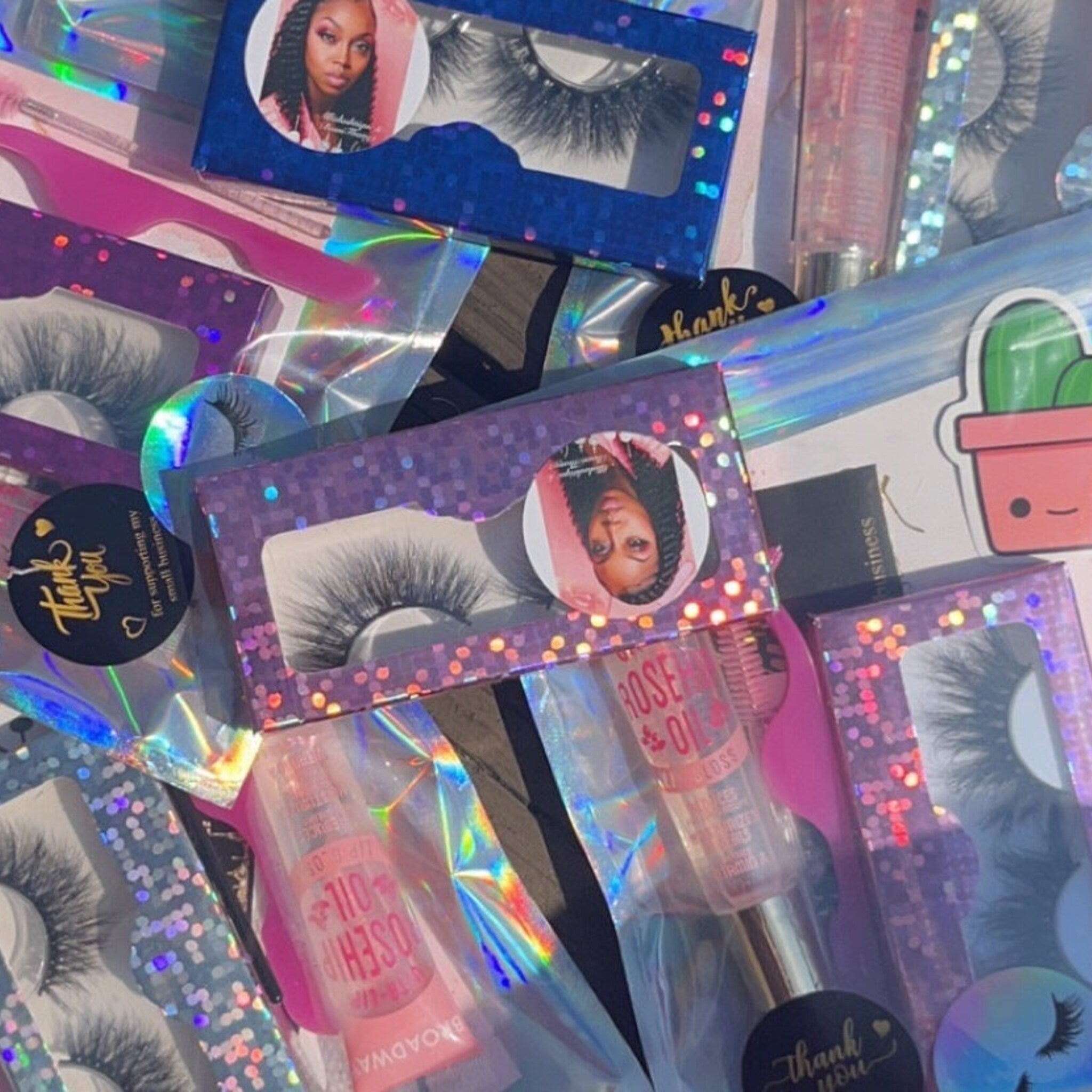 False eyelashes in black, purple and blue boxes with holographic packaging and lip gloss