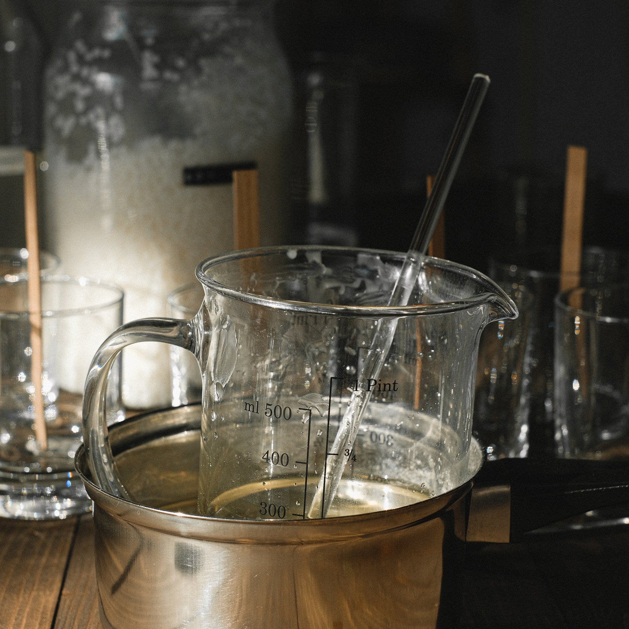Glass measuring beaker with clear glass, liquid inside, and metal pot underneath