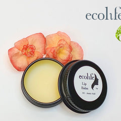 Lip balm in black metal tin, Ecolife Cosmetics lip balm with flowers in background
