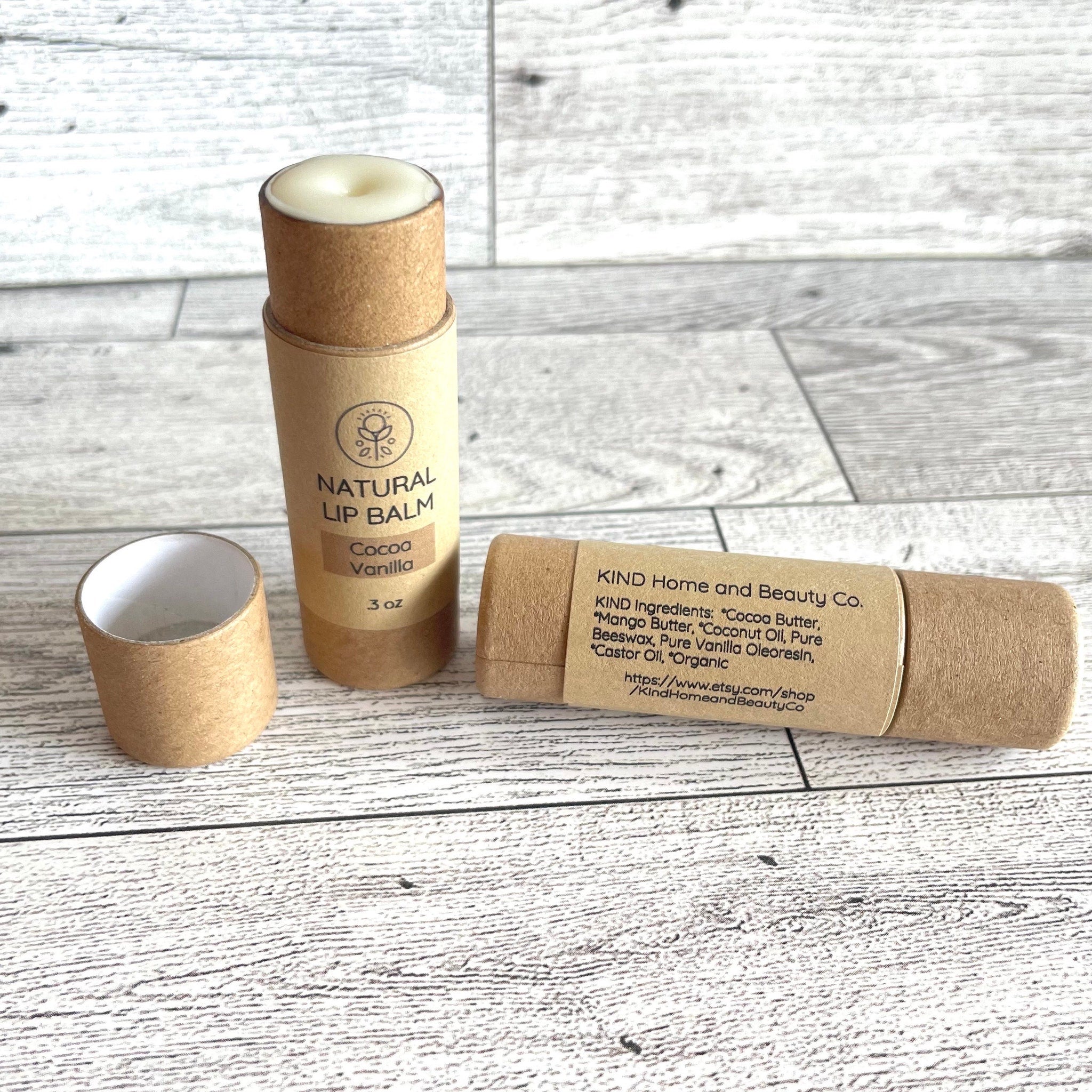 Lip balm tubes in brown cardboard with white lip balm, Kind Home & Beauty Co. branding visible