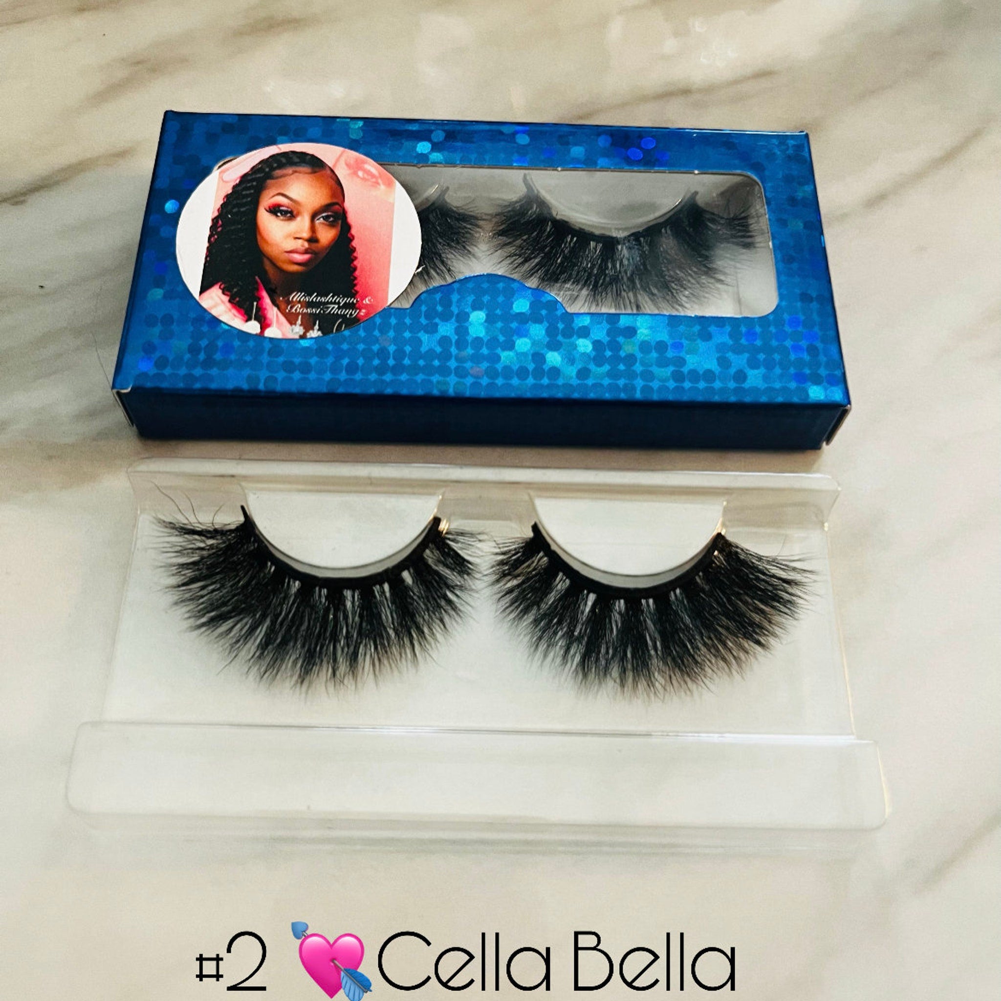 False eyelashes with black lashes, blue glitter box, and Cella Bella branding