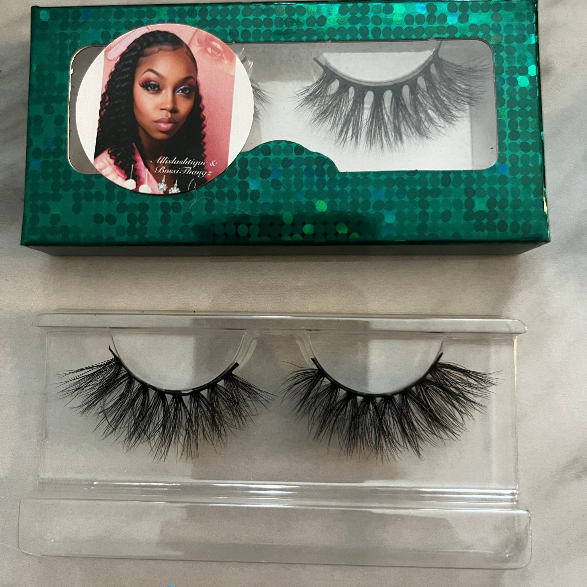 False eyelashes with black synthetic fibers in clear plastic packaging and green box, Allashashique & Bossi Thangz brand