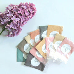 Close-up of vegan mineral eye shadow samples in assorted matte and shimmer shades with eco-friendly paper packaging