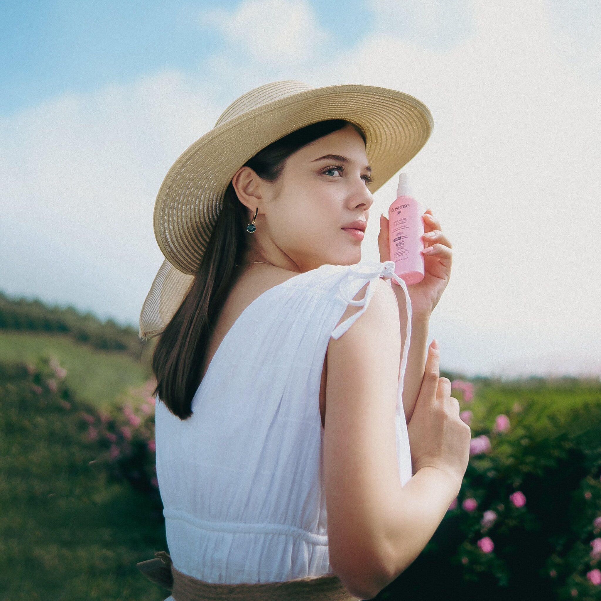 Rosense spray bottle held by woman wearing white dress and straw hat