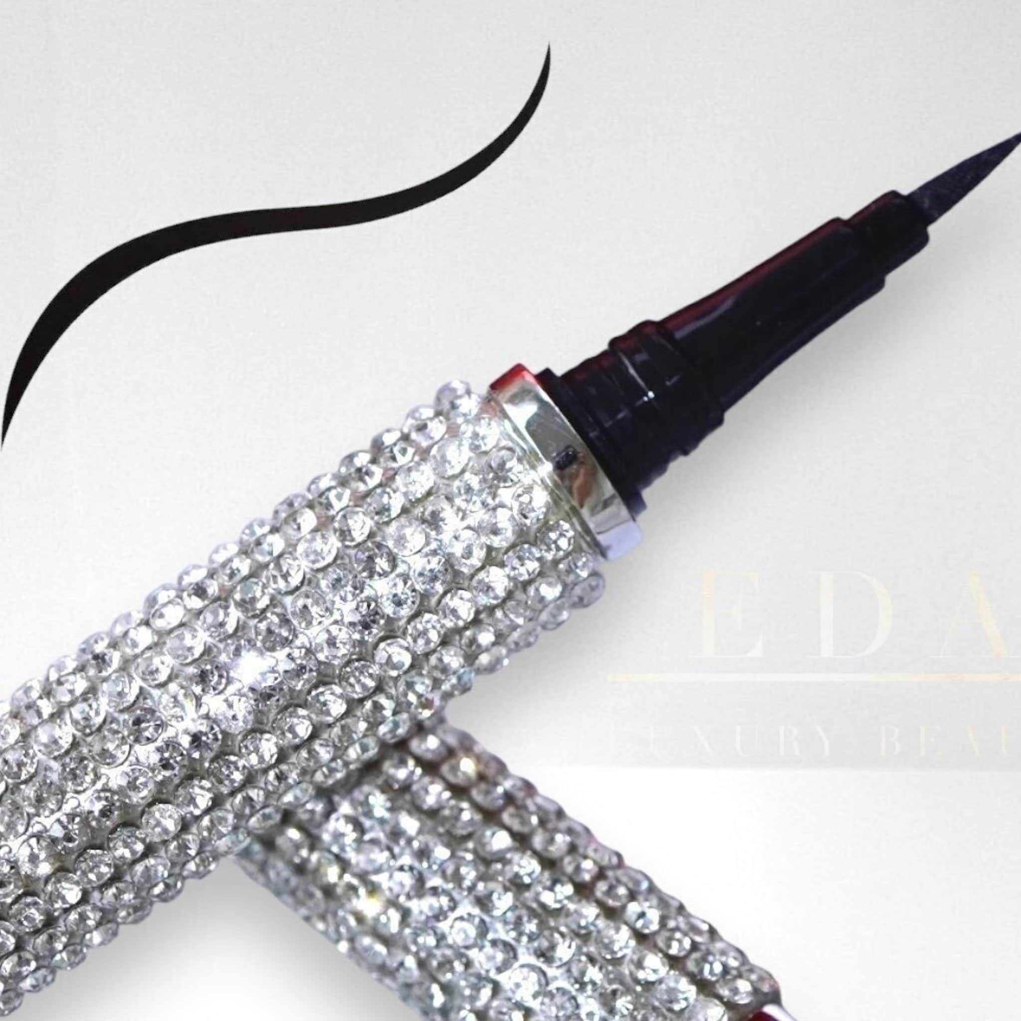 Liquid eyeliner black with rhinestone-covered barrel, EDA LUXURY BEAUTY brand visible, and black eyeliner stroke
