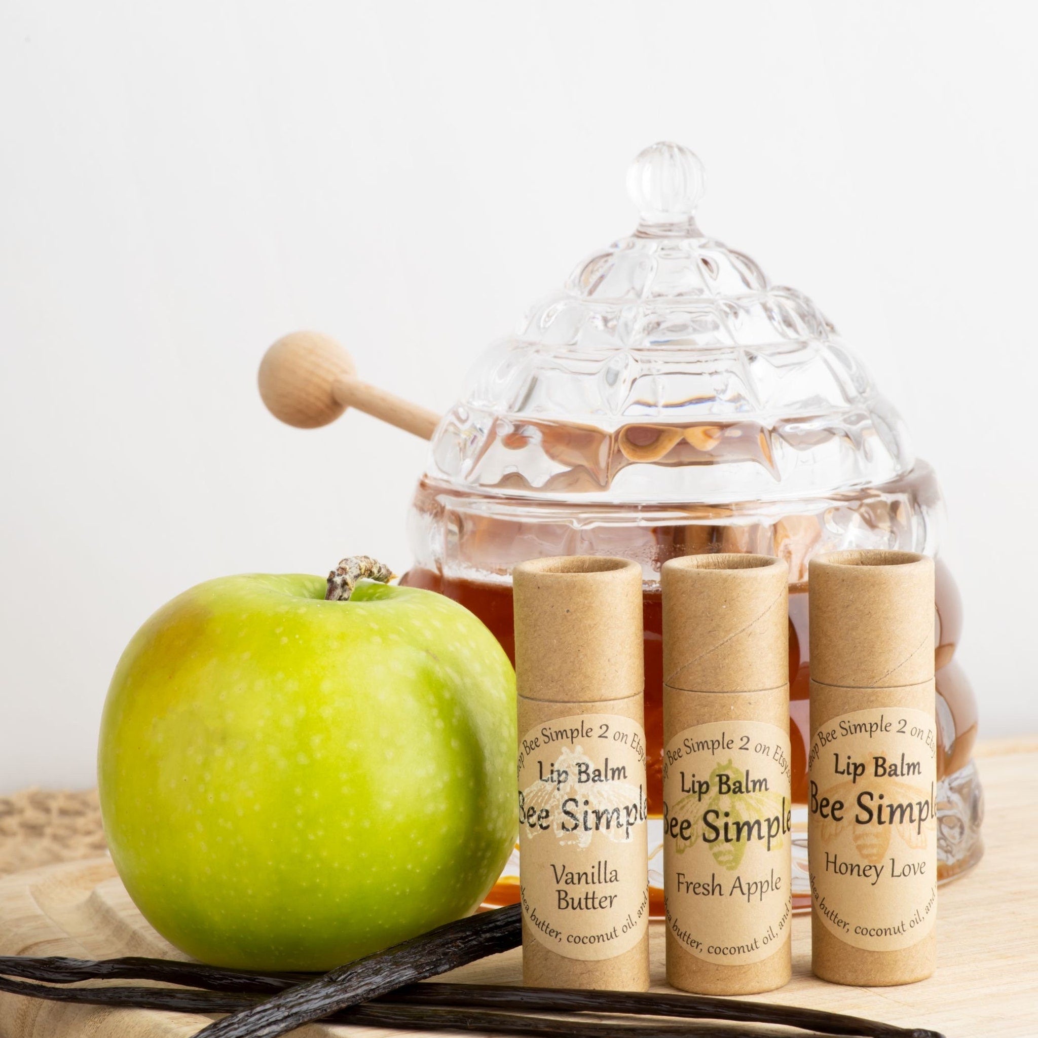 Lip balm tubes with brown paper packaging, Bee Simple brand text, and green apple next to them