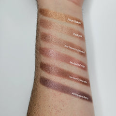 Close-up of shimmering beige blush eyeshadow with baked texture and soft golden flecks in compact pan