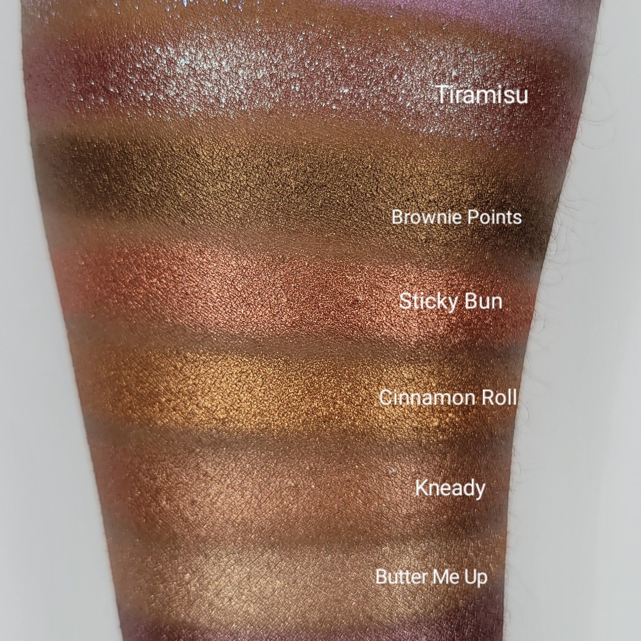 Side view of Cinnamon Roll Bronze Shimmer Eyeshadow pan showing warm bronze tones and reflective shimmer particles