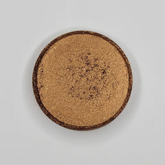 Close-up of Cinnamon Roll Bronze Shimmer Eyeshadow in round compact with warm bronze sparkle and smooth satin finish