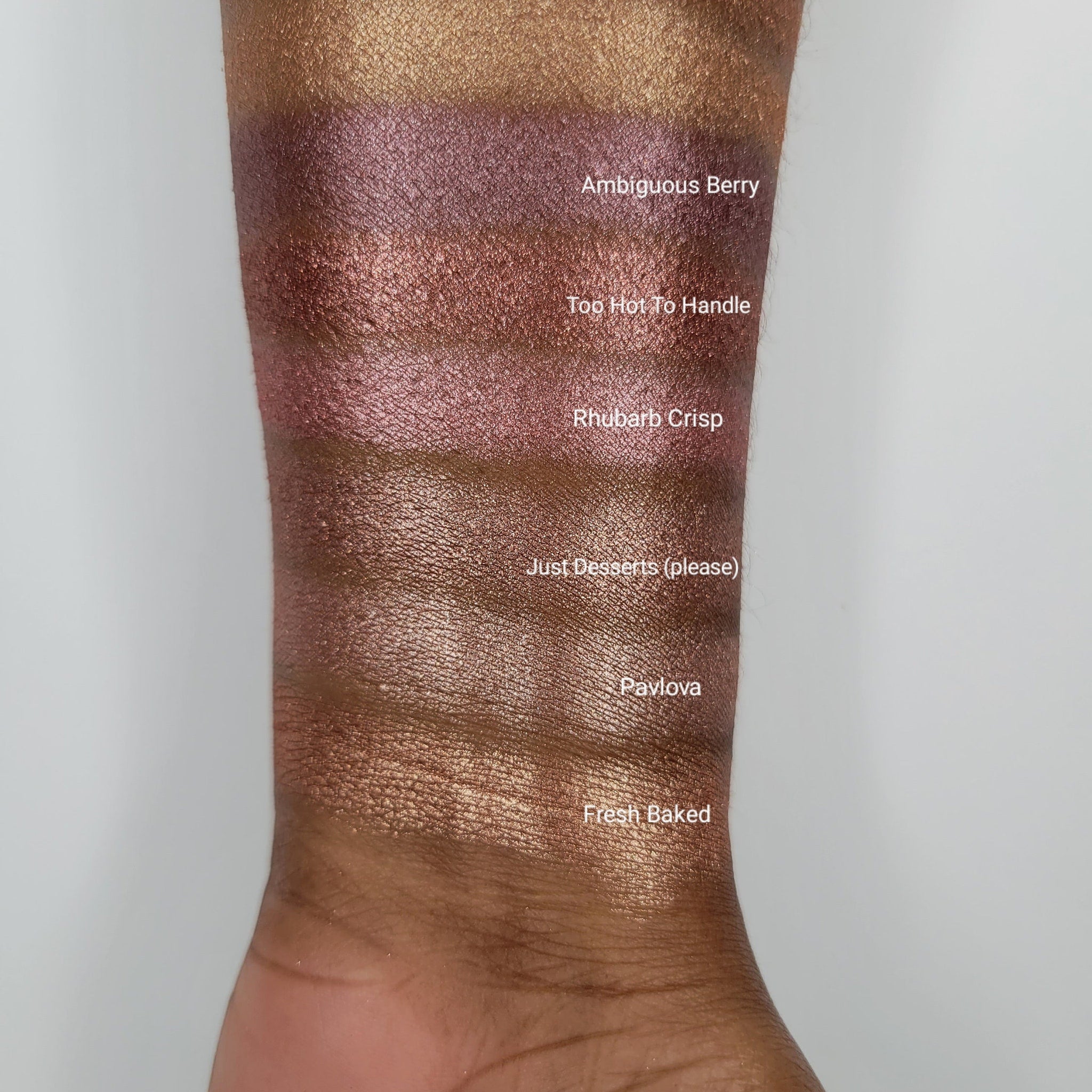 Side view of shimmer eyeshadow bundle showing six pans in pink, brown, and red hues with reflective finish