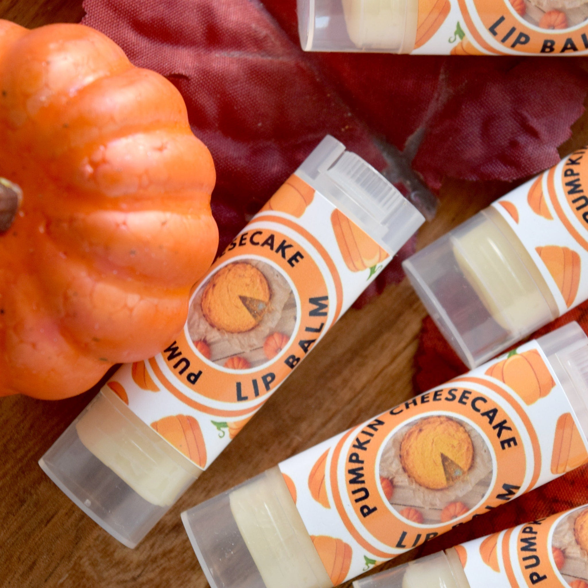 Lip balm tubes with orange and white labels, pumpkin cheesecake design, and clear plastic caps