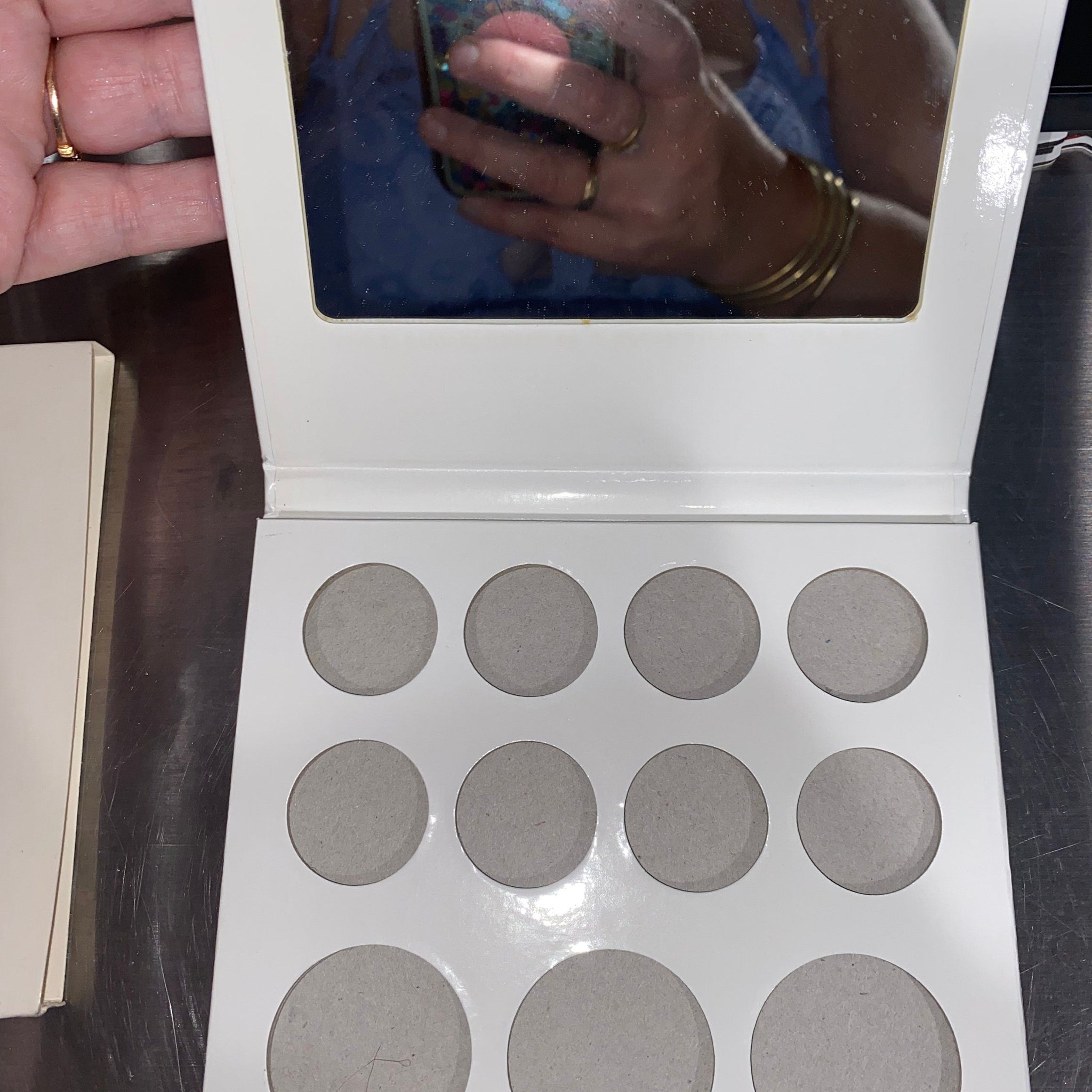 Side view of 11-pan eyeshadow palette showing mirror and gradient of matte to shimmer shades in warm neutrals