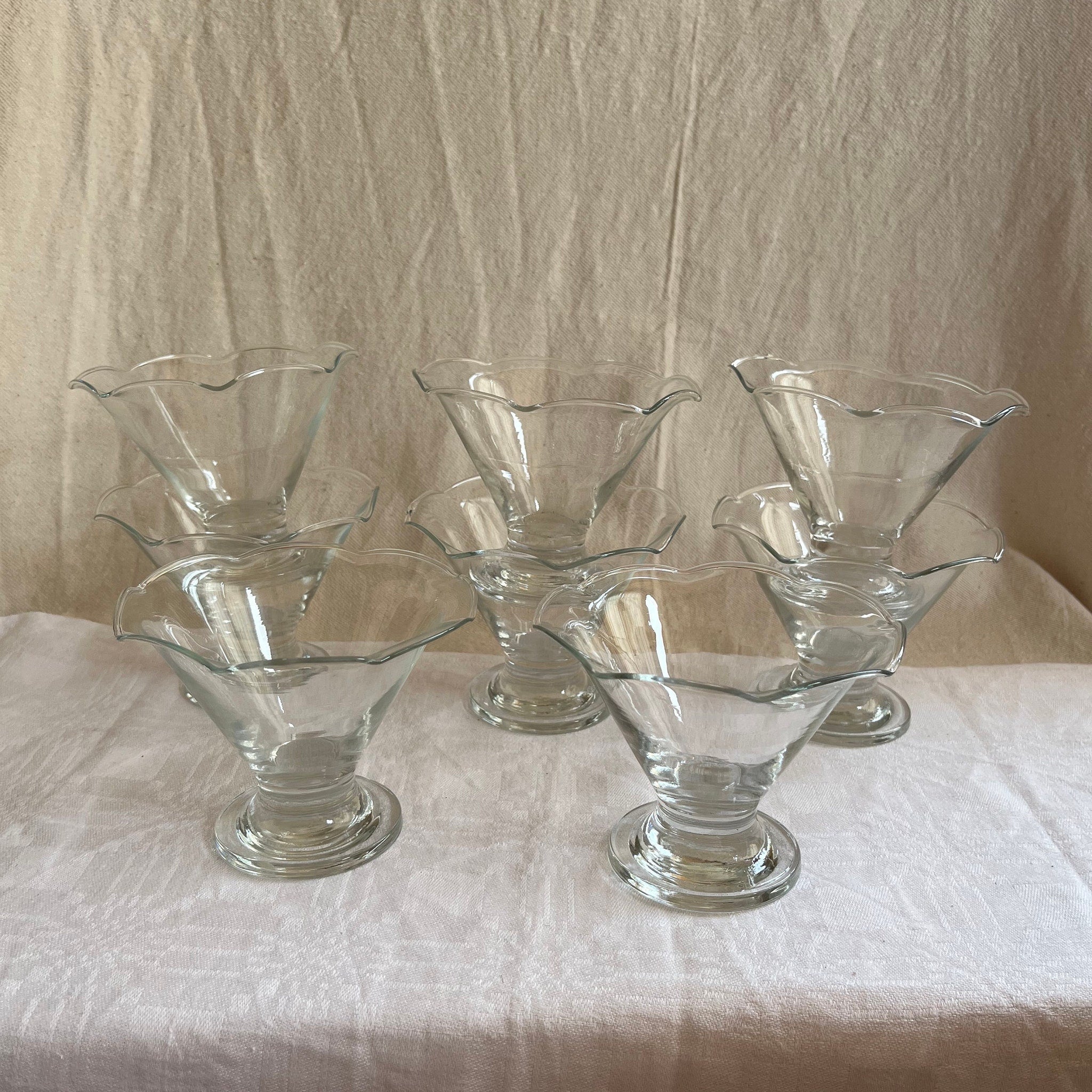 Dessert glasses clear glass footed with scalloped rims, on white tablecloth