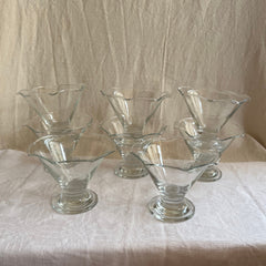 Dessert glasses clear glass footed with scalloped rims, on white tablecloth