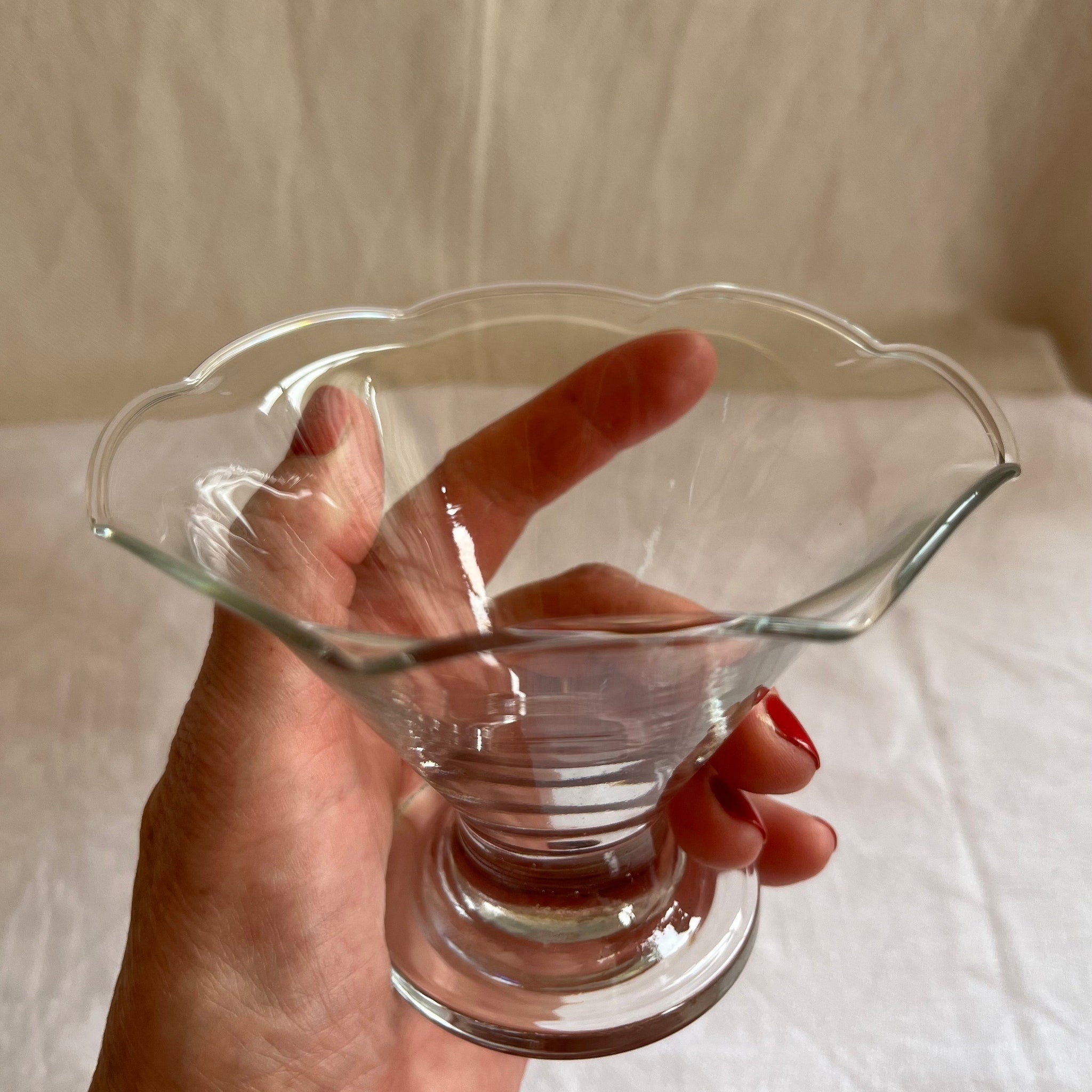 Glass dessert dish, clear glass, scalloped rim, held in hand