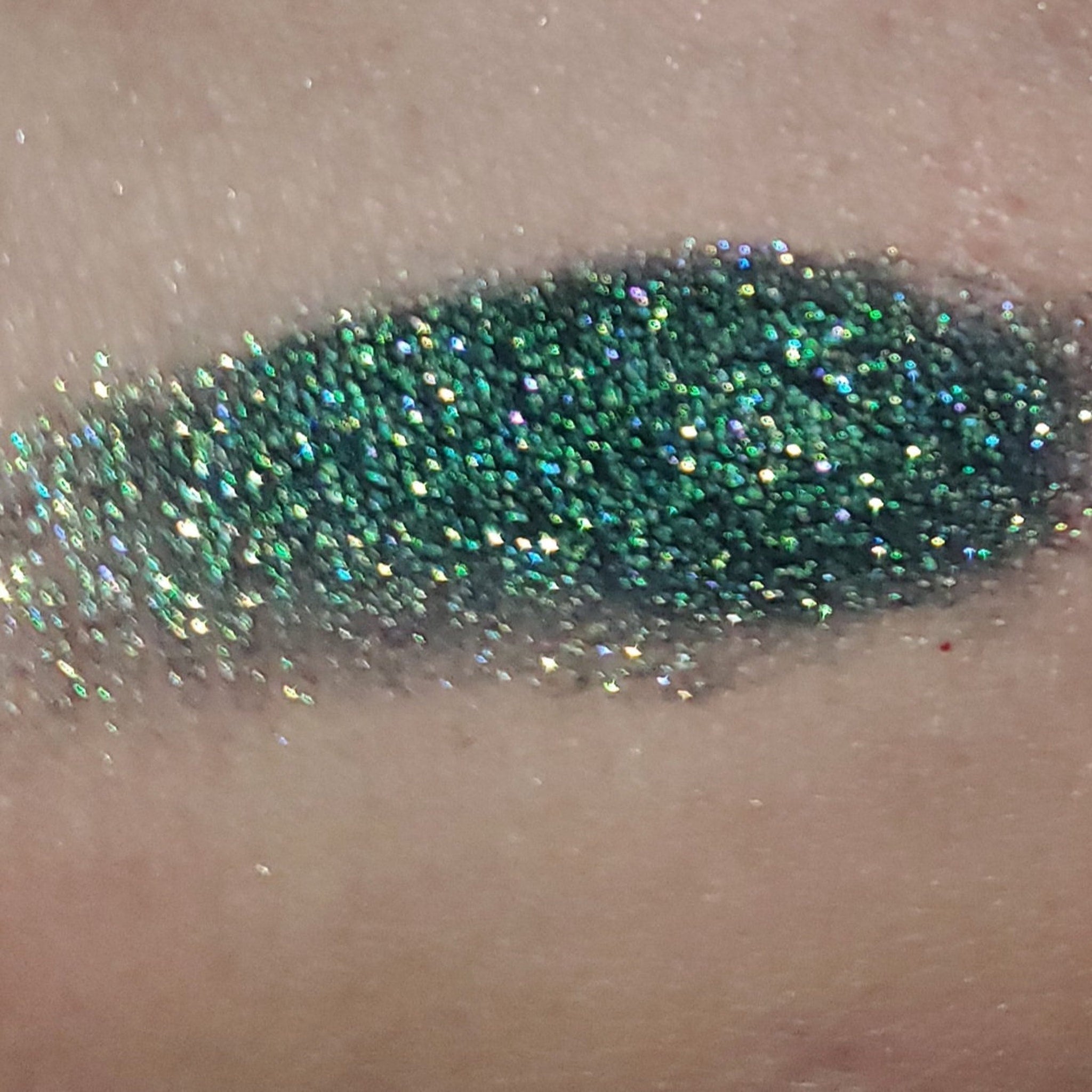 Close-up of fingertips applying shimmery taupe eyeshadow to eyelid with soft blending motion