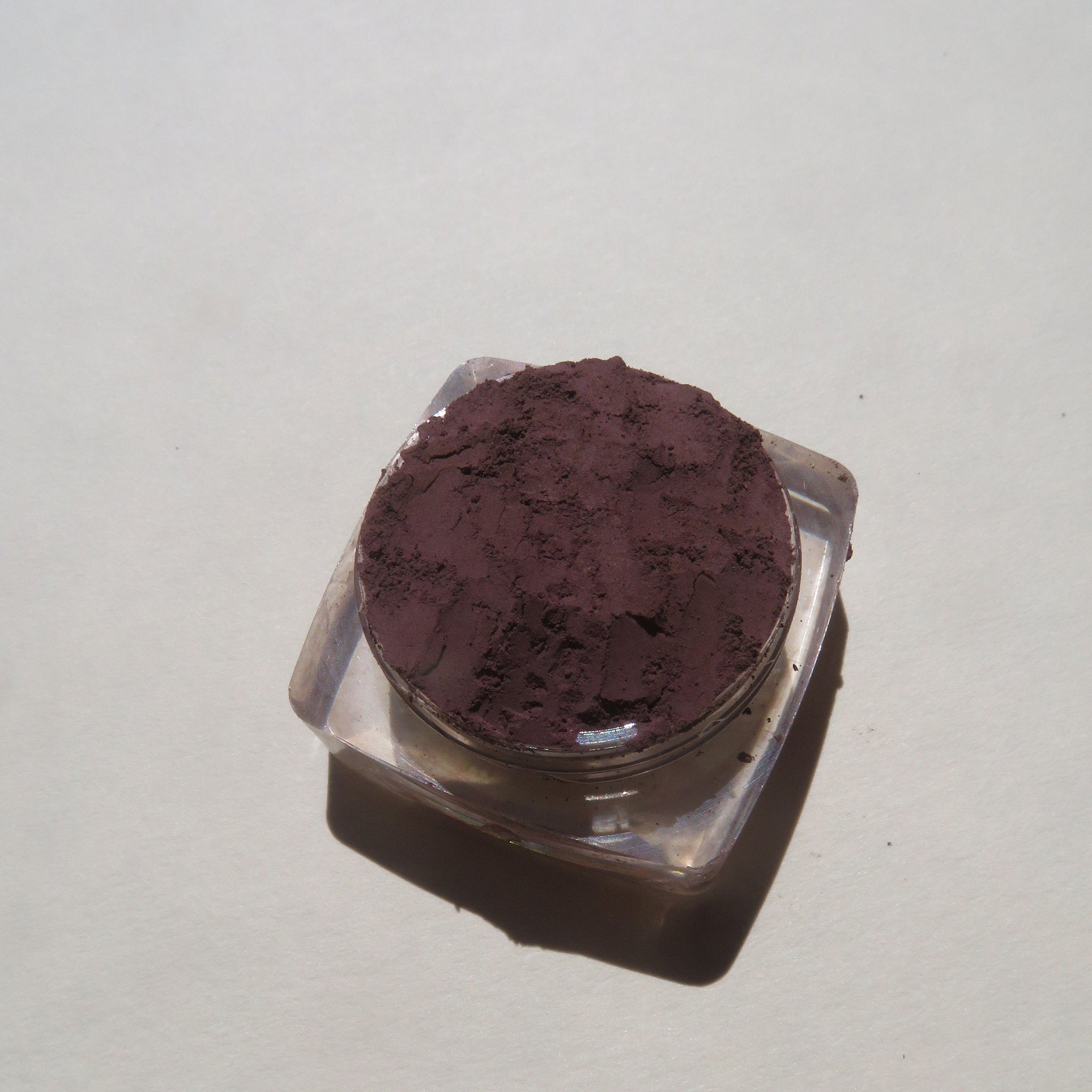 Open jar of Earth Angel loose mineral eyeshadow showing super dark muted purple powder with matte finish