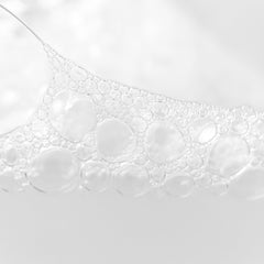 Soap bubbles, white transparent spheres, close-up view of foam and liquid surface
