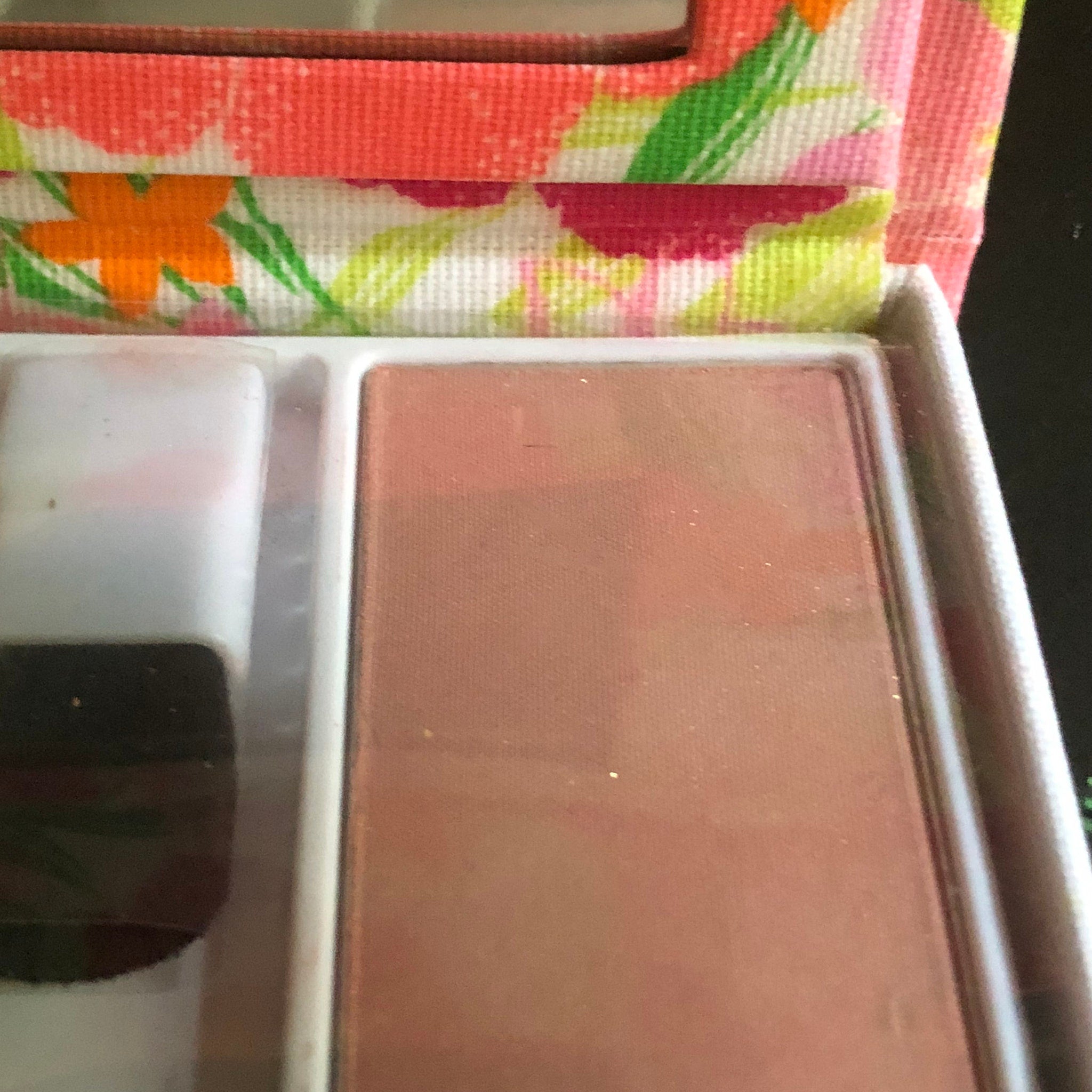 Blush compact with coral and floral fabric, blush color, and brush visible