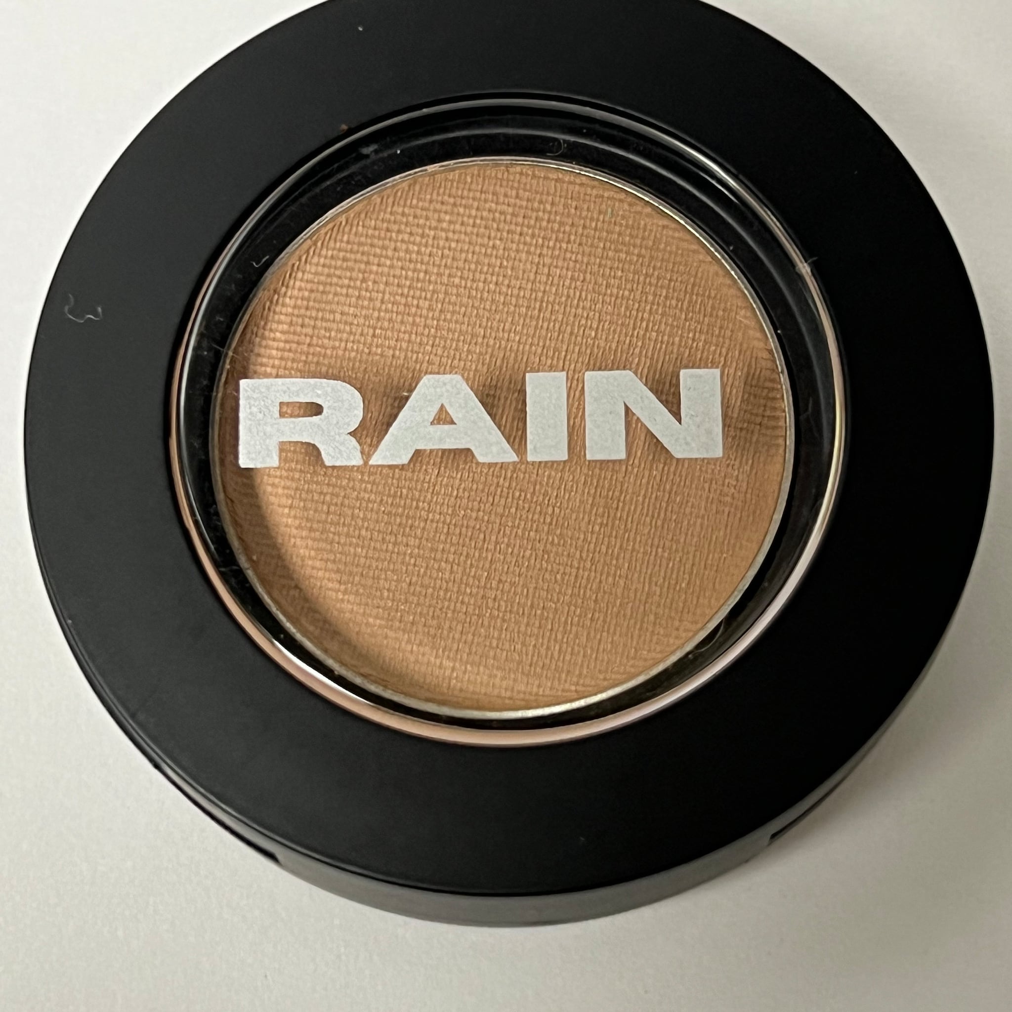 Square compact of suede matte eye shadow in warm taupe shade with smooth texture and minimalist packaging