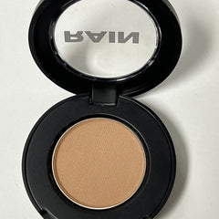 Close-up of matte taupe eyeshadow pan with smooth suede texture in compact case