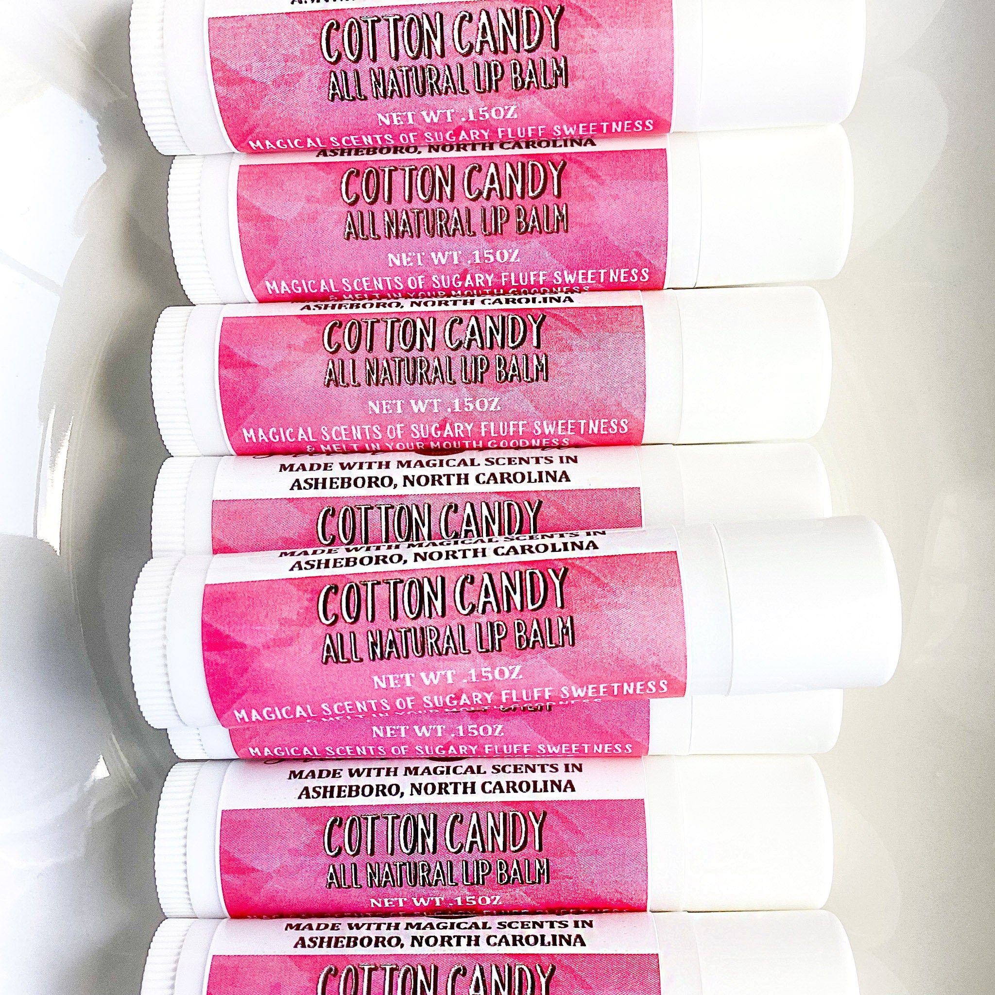 Lip balm tubes with pink label, white tube, and Cotton Candy text visible