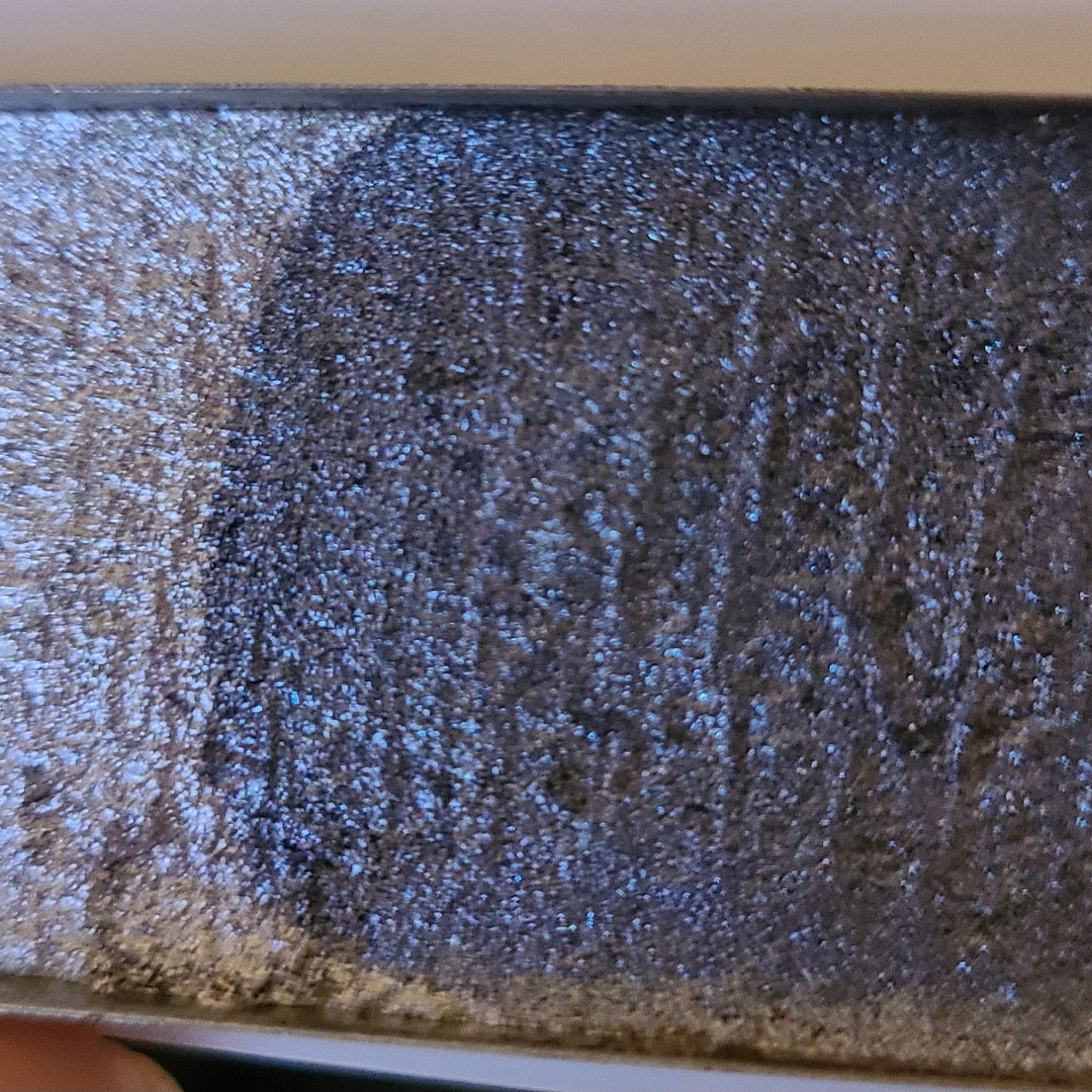 Close-up of fingertips applying multichrome eyeshadow to eyelid, showing iridescent color shift from purple to green.
