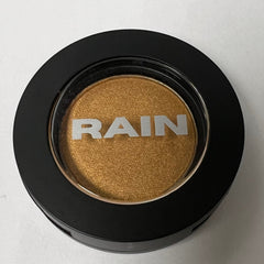 Close-up of sparkling gold pressed powder eye shadow in a sleek black compact with gold trim