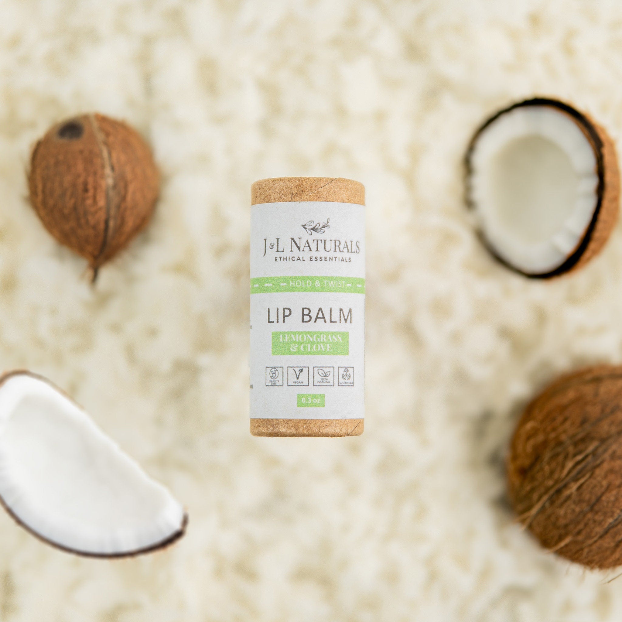 Lip balm tube with white and green label, brown cardboard top, and J&L Naturals text visible