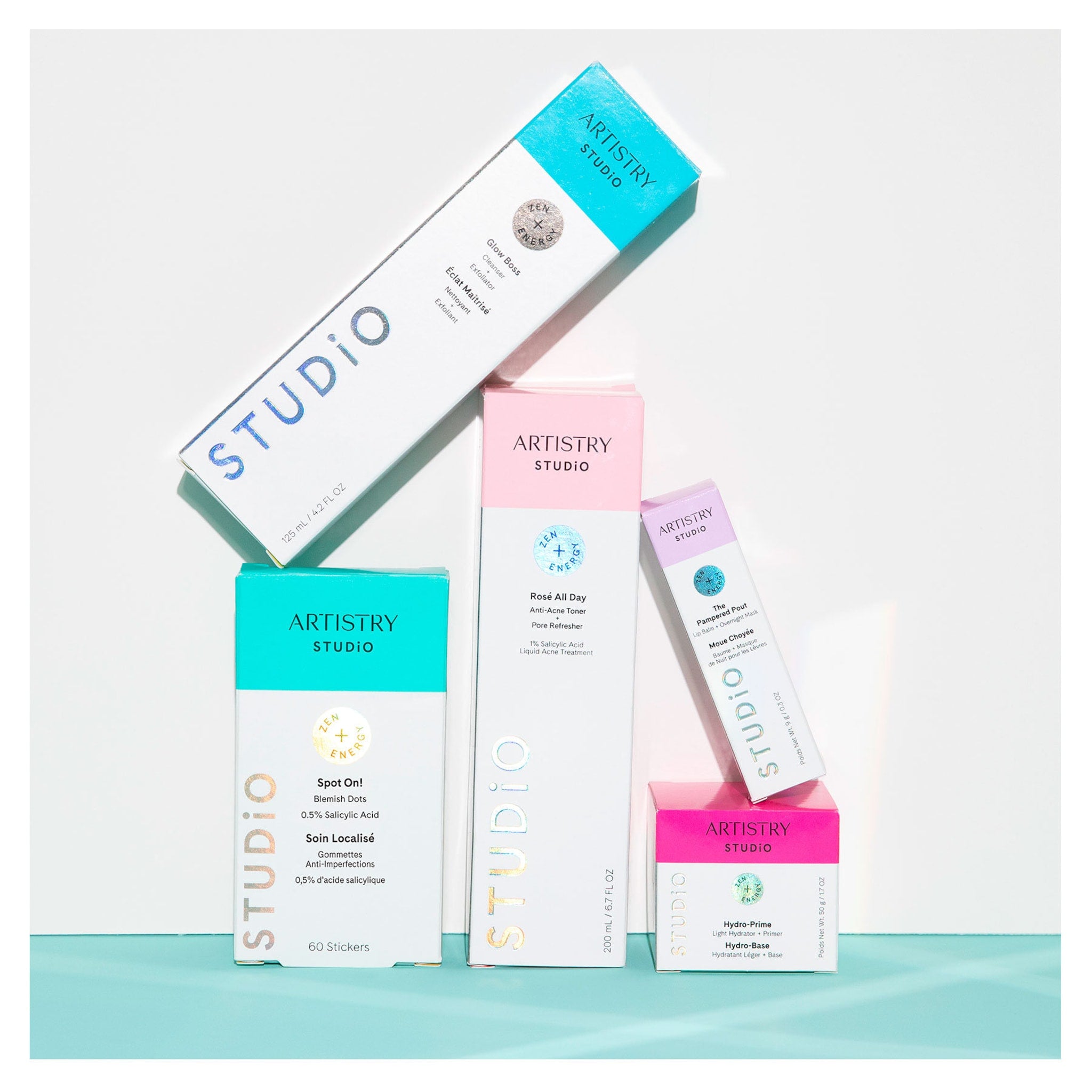 Skincare product boxes in white, pink, teal, and purple with ARTISTRY STUDIO branding on white background
