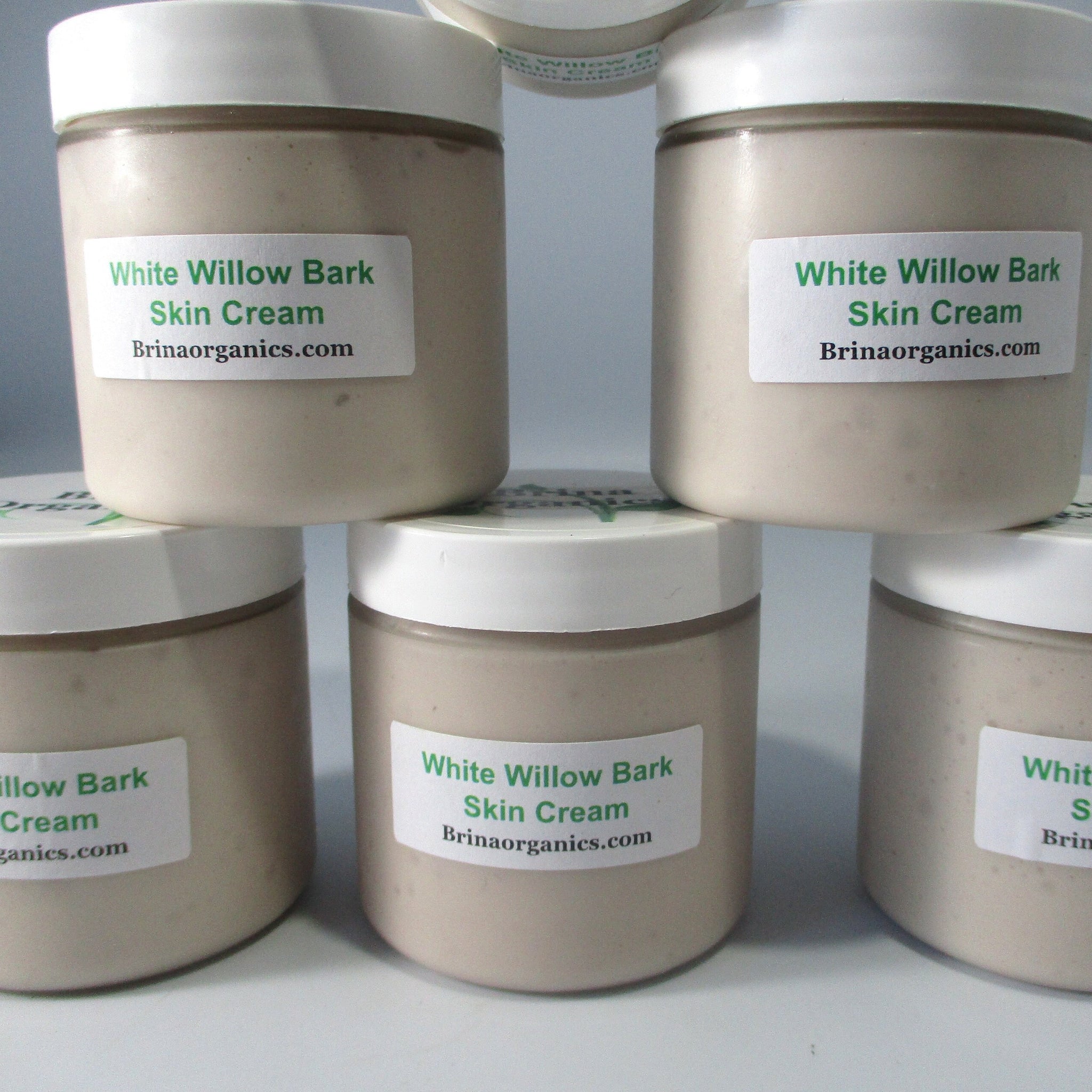 Skin cream jars with white lids, beige cream, and Brinaorganics labels, stacked together