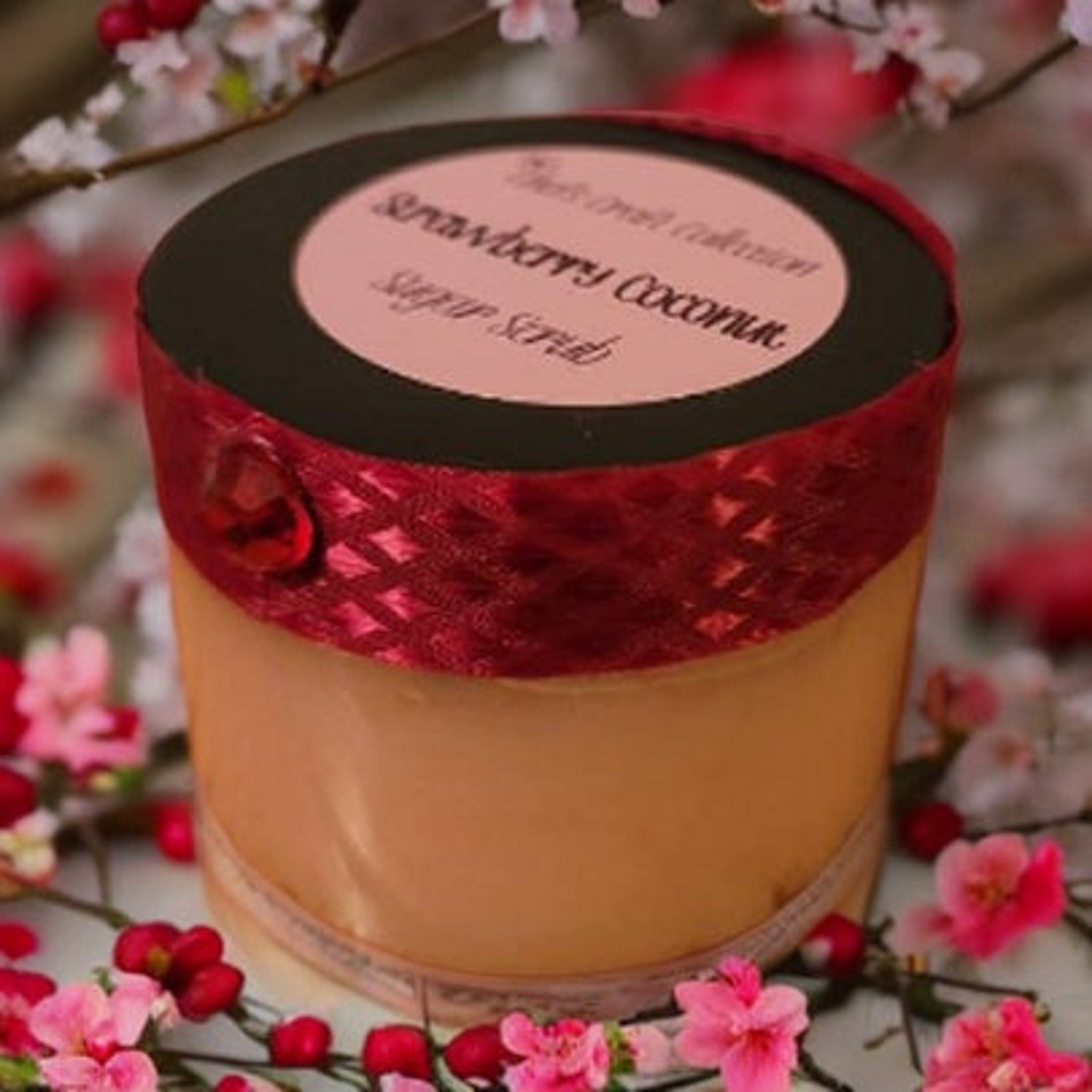 Sugar scrub jar with red ribbon, pink label, and floral accents around it