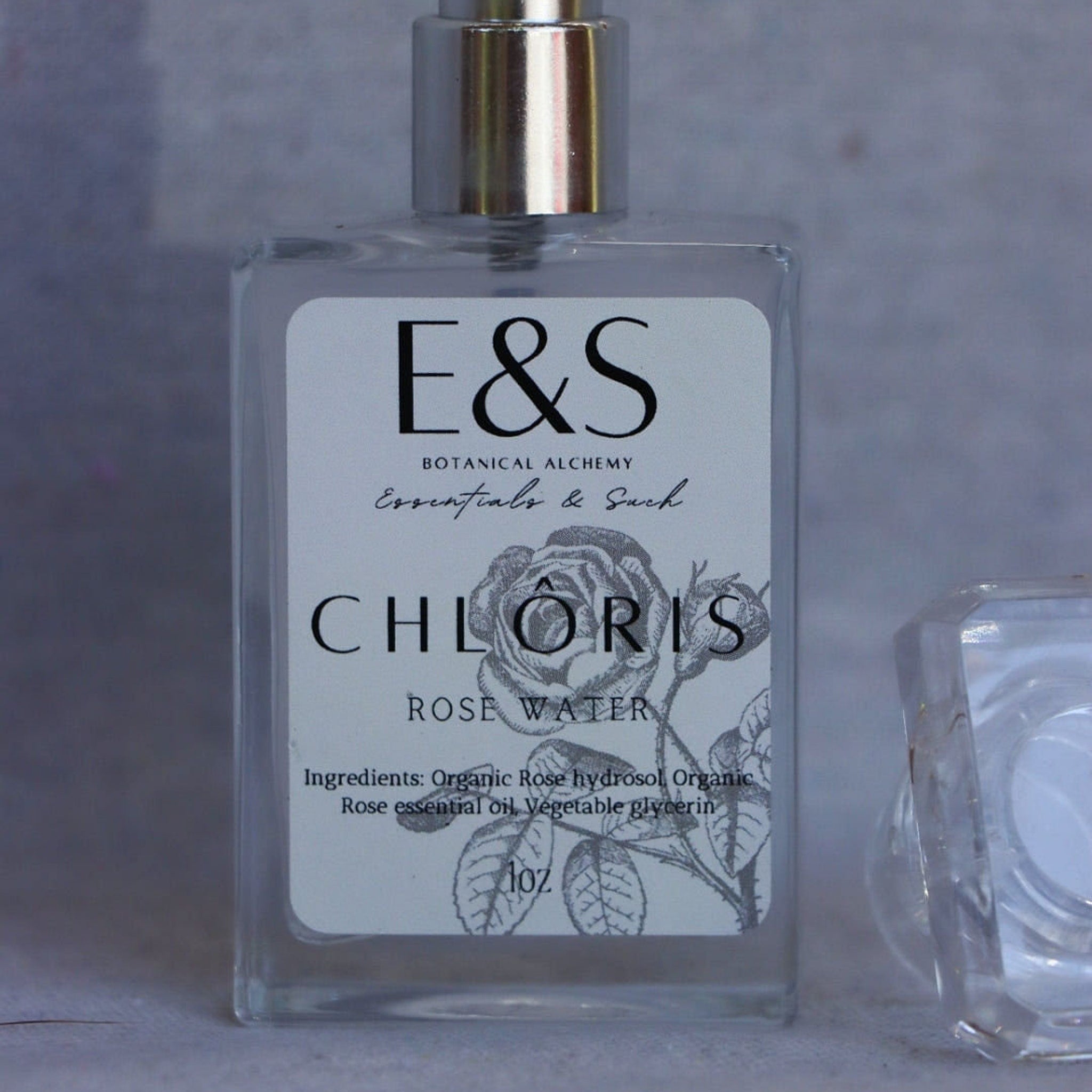 Rose water bottle with silver cap, clear glass, and E&S label with floral design