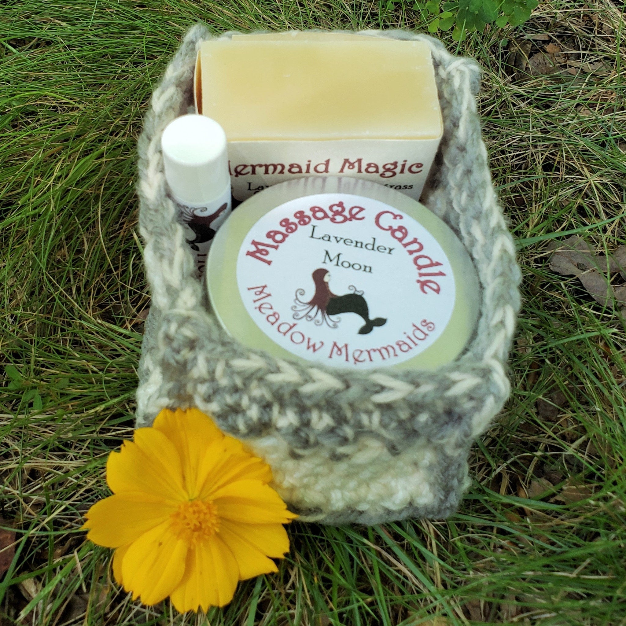 Soap and candle gift set with gray knitted basket, yellow bar soap, and yellow flower in grass