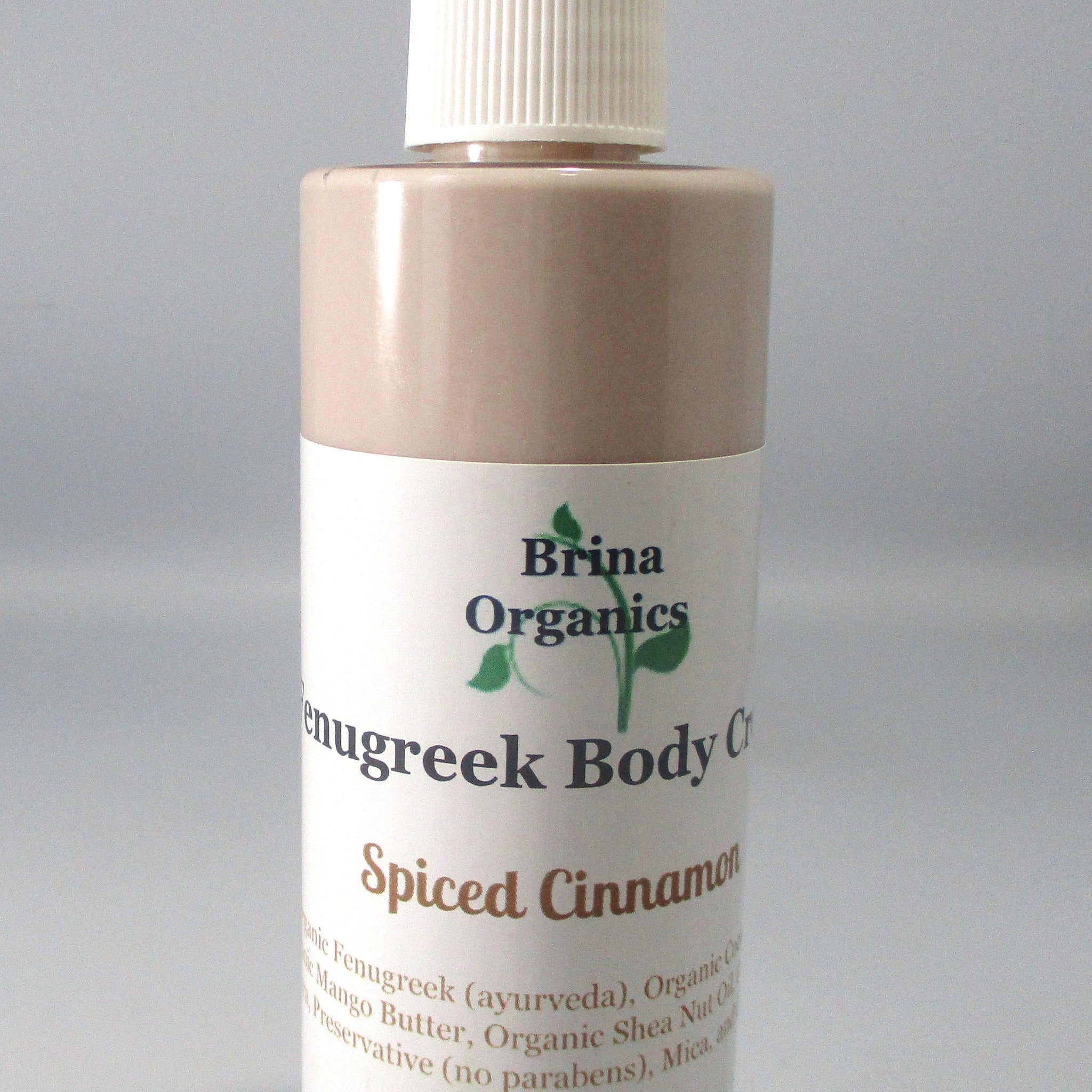 Body cream bottle with white label, light brown body, and white cap, Brina Organics text visible