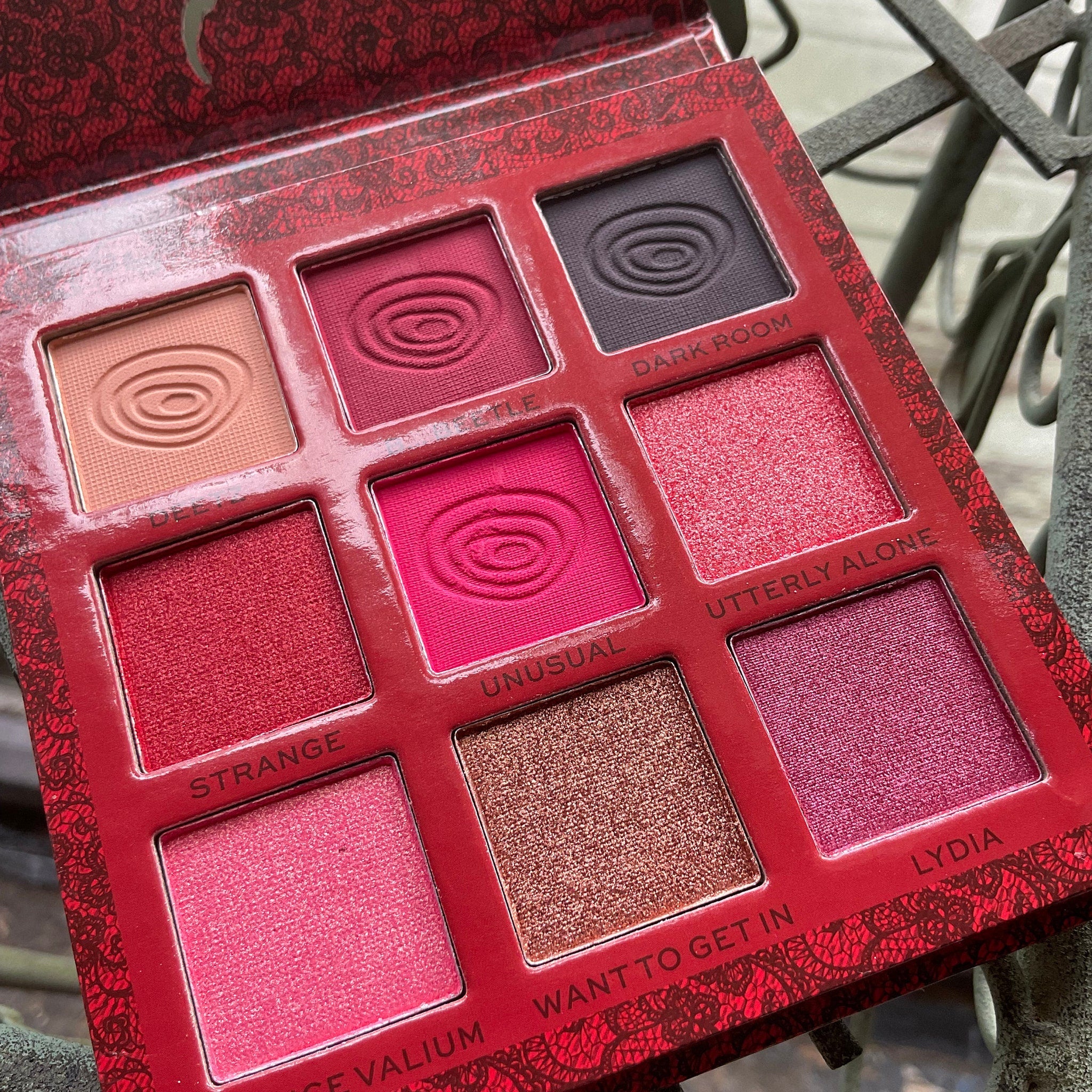 Side view of Beetlejuice eyeshadow palette showing purple and green matte shades with black packaging