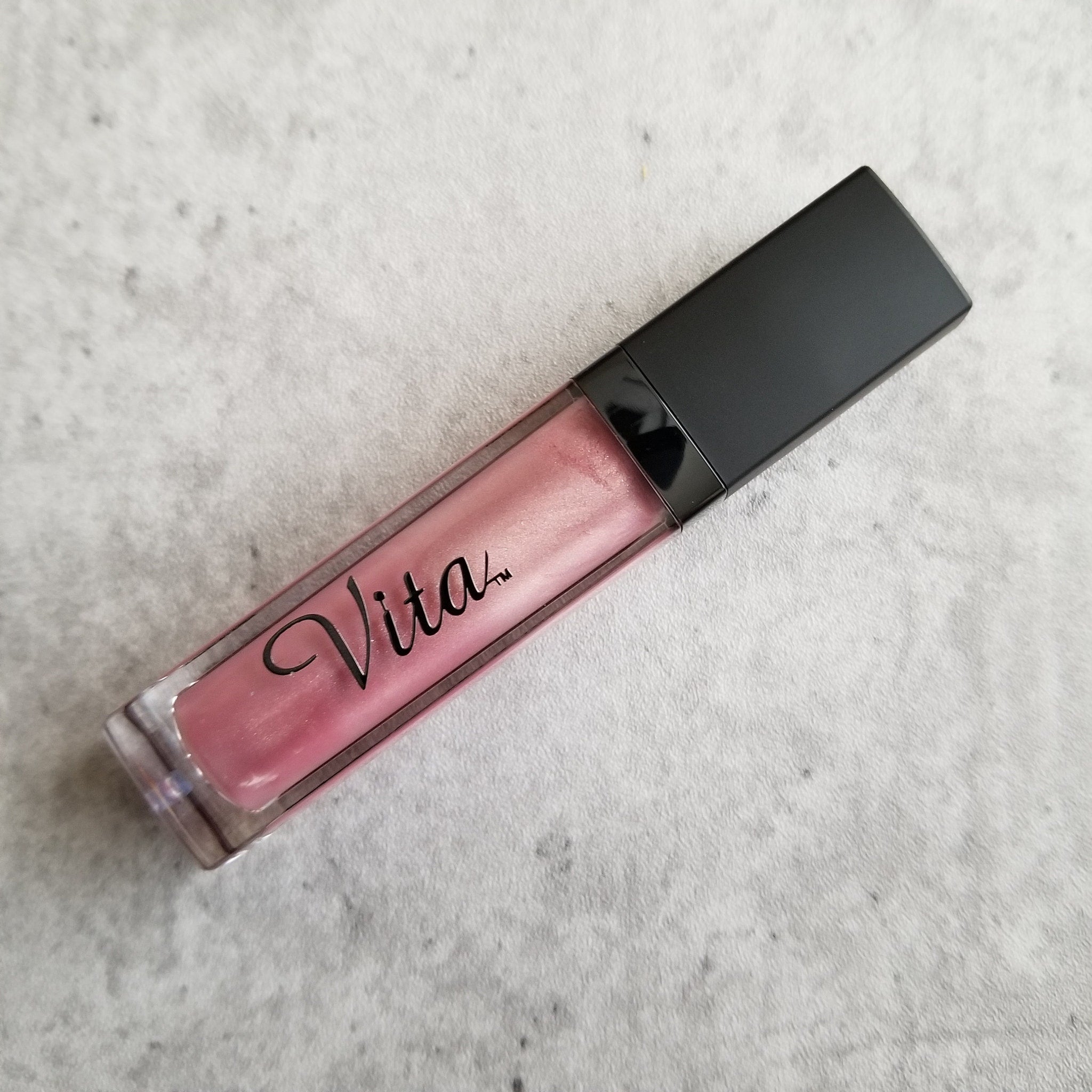 Lip gloss tube with pink gloss, black cap, and Vita brand name visible