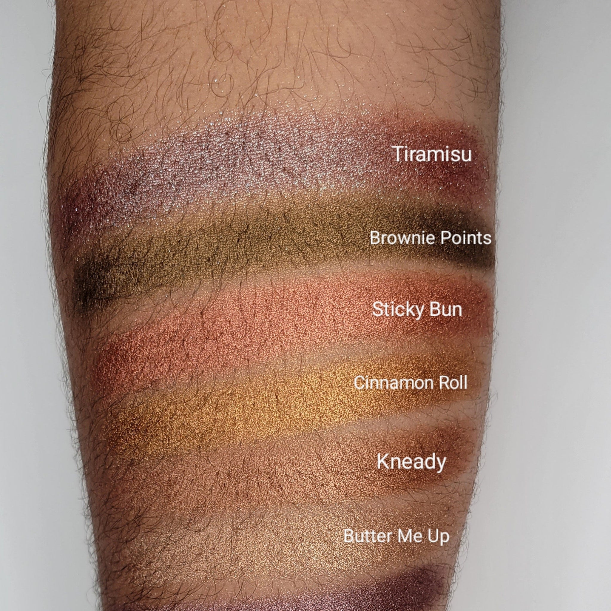 Side view of Cinnamon Roll Bronze Shimmer Eyeshadow pan showing warm bronze powder with golden sparkles