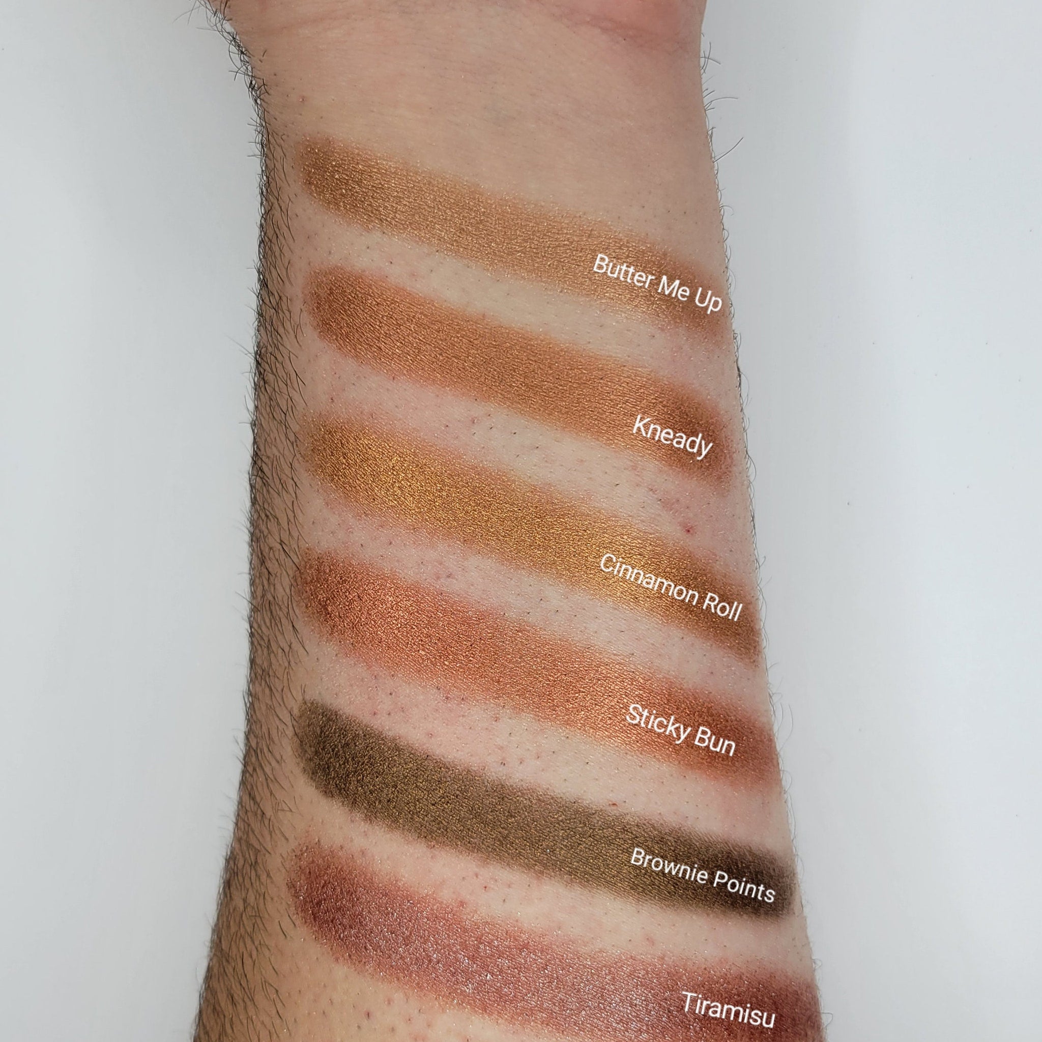 Close-up of cinnamon bronze shimmer eyeshadow with warm golden sparkles in compact pan